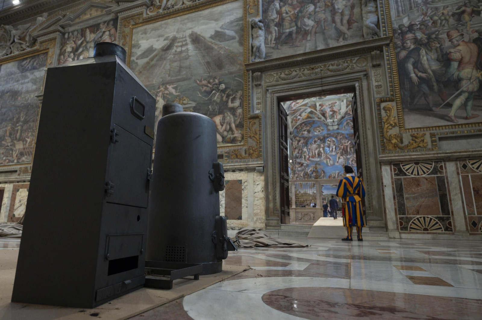 Guardias suizas vigilan la instalación de las estufas en la Capilla Sixtina para el cónclave.