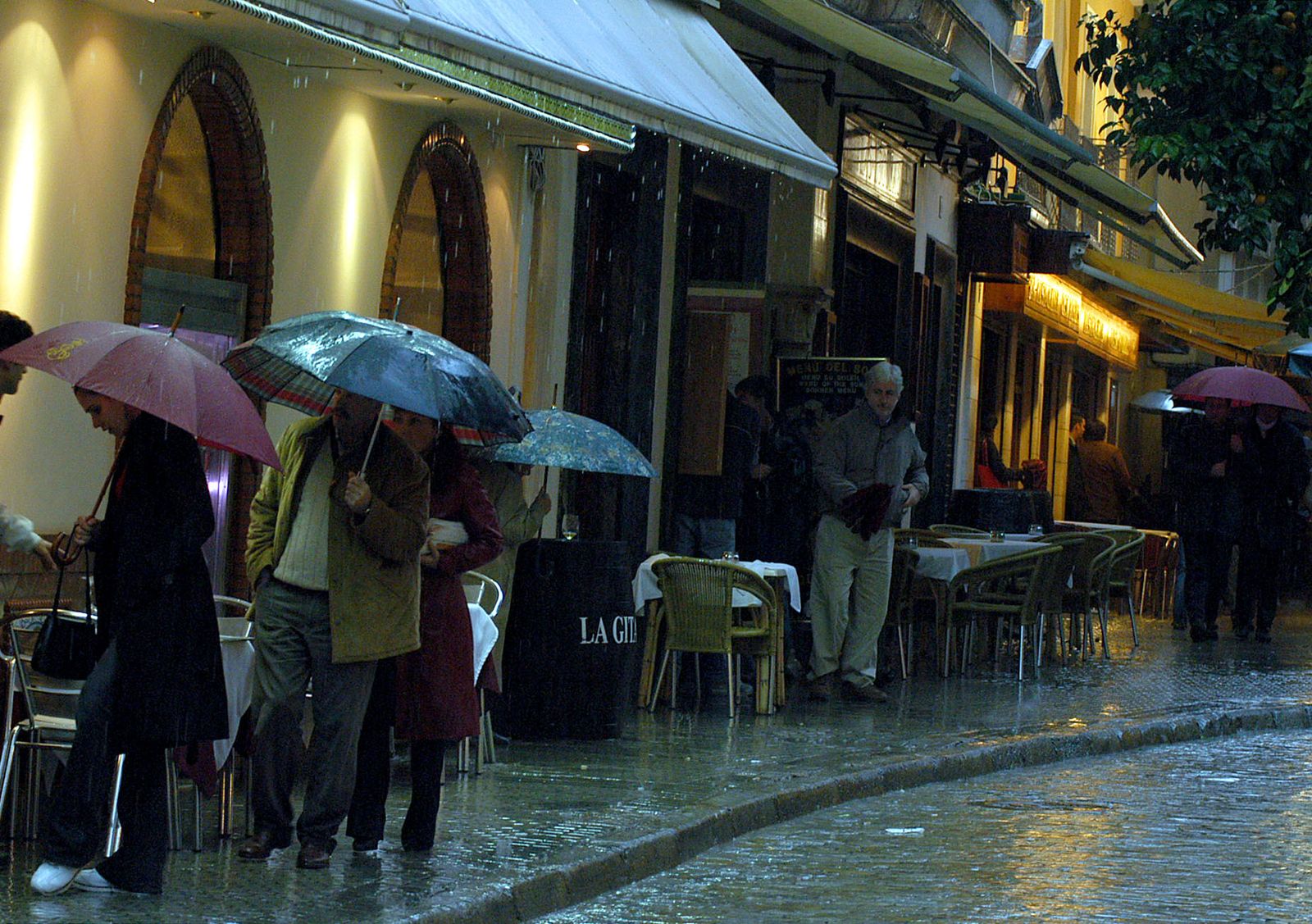 Varias personas se protegen de la lluvia en Sevilla
