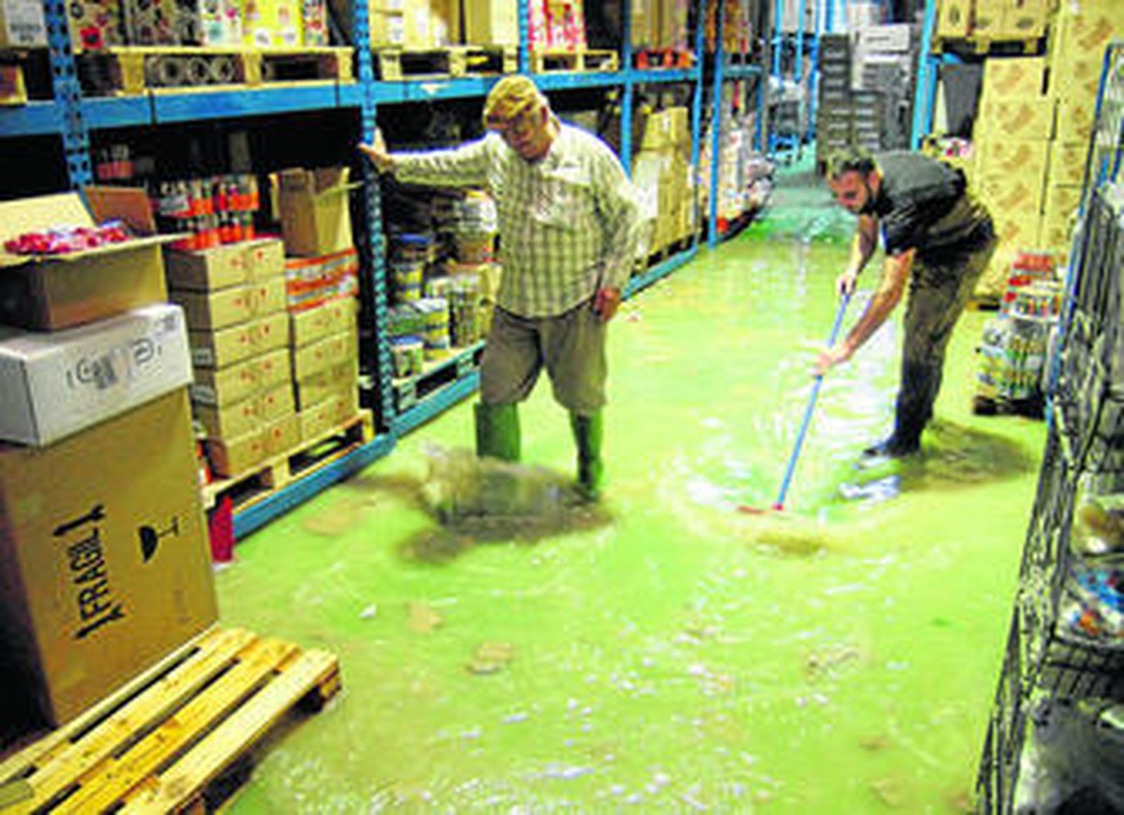 Los propietarios de un comercio intentan retirar parte del agua acumulada en su establecimiento con ocasión de las lluvias de marzo.