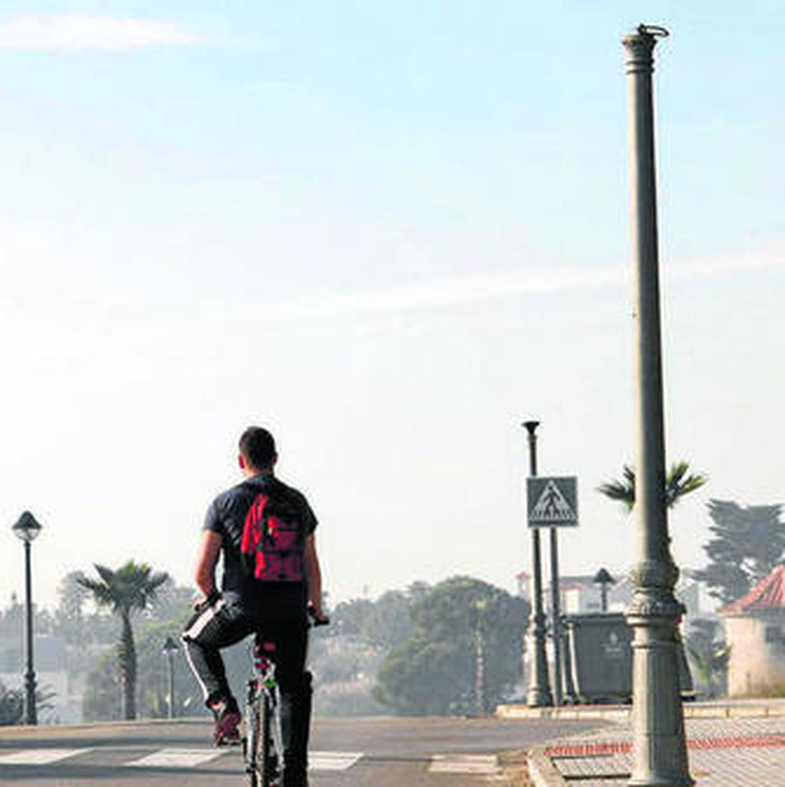 Un joven ciclista  ayer, al lado de las farolas esquilmadas en Conil.