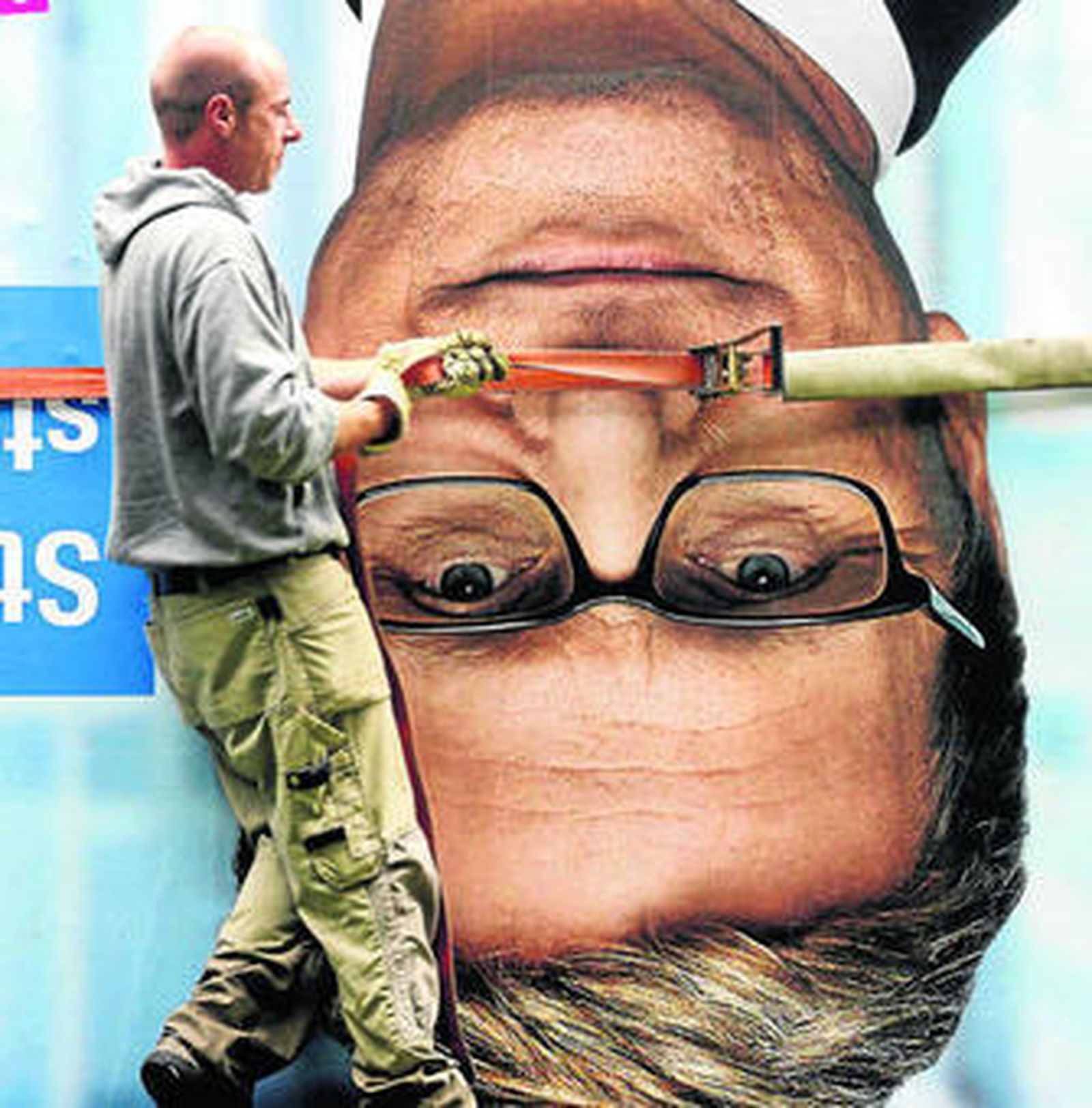 Un operario retira un cartel con la imagen del liberal Guido Westerwelle, ministro de Exteriores alemán.