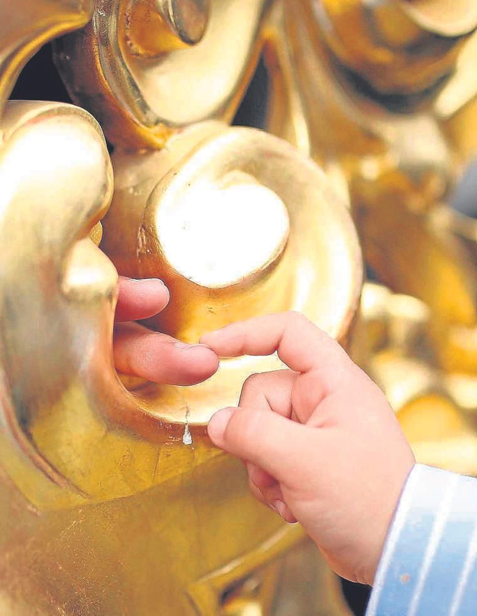 Un pequeño toca el dedo de un costalero a través de los respiraderos del misterio de El Transporte.