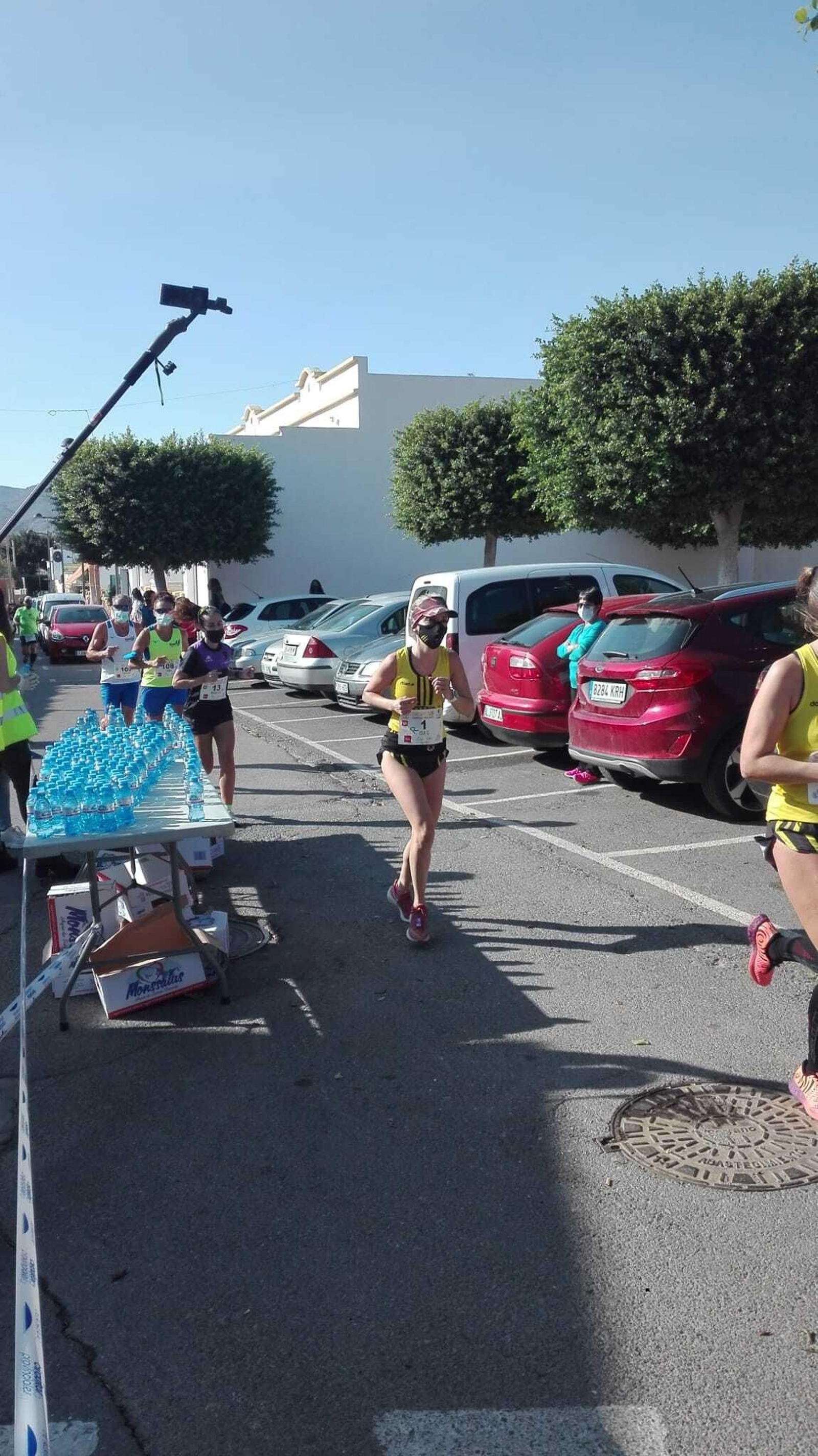 Corredores con mascarilla al pasar por el avituallamiento.