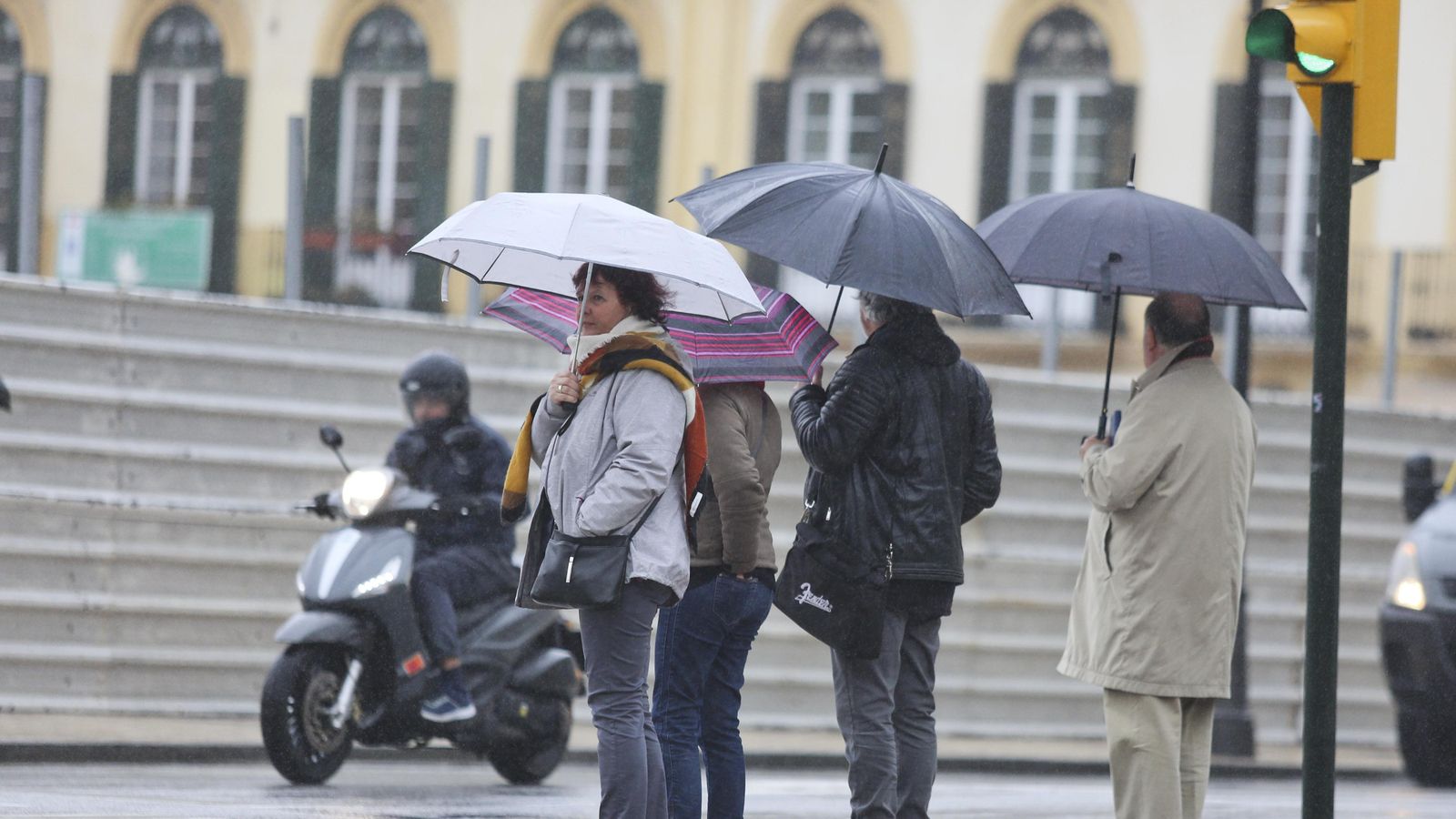 Varias personas esperan con sus paraguas para cruzar una calle en Málaga.