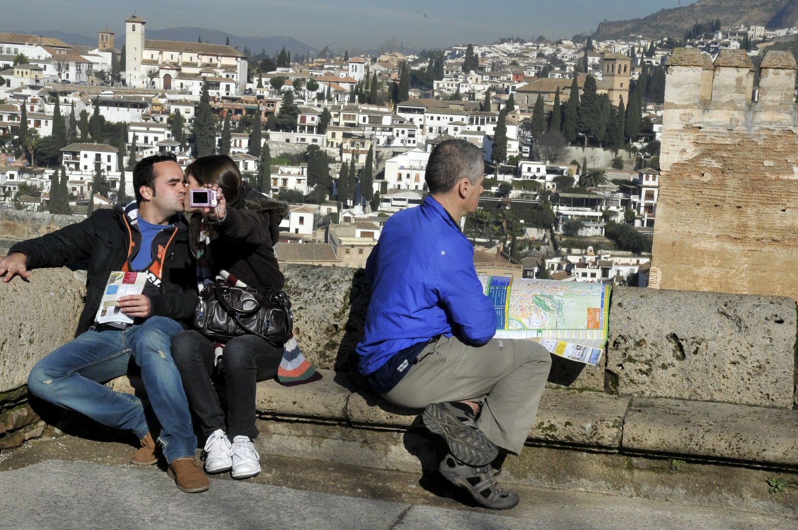 Unos turistas se fotografían en uno de los miradores del conjunto de la Alhambra, con el barrio del Albaicín al fondo.