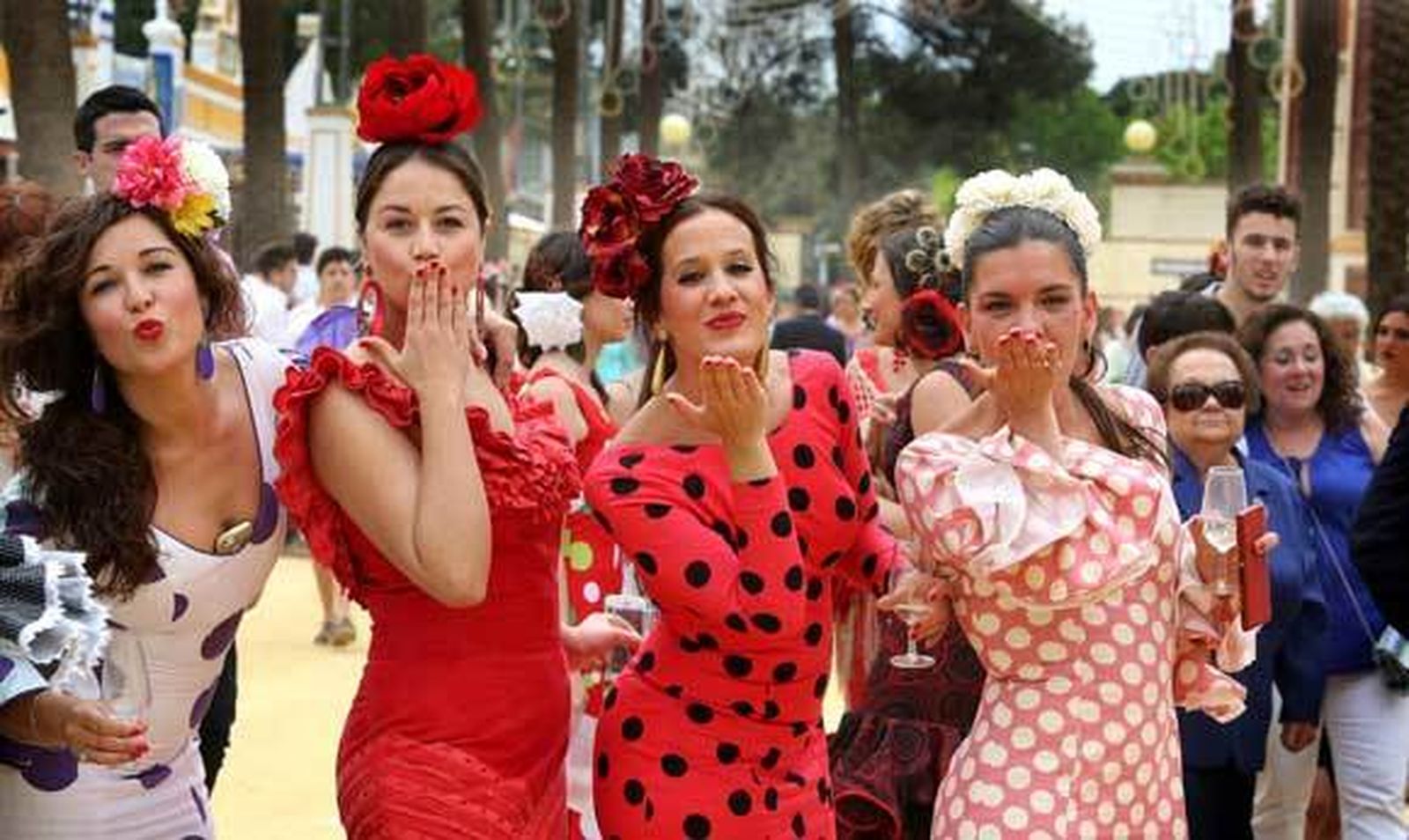 Un grupo de jóvenes vestidas de flamenca lanzan un beso al aire en pleno Real. /Pascual