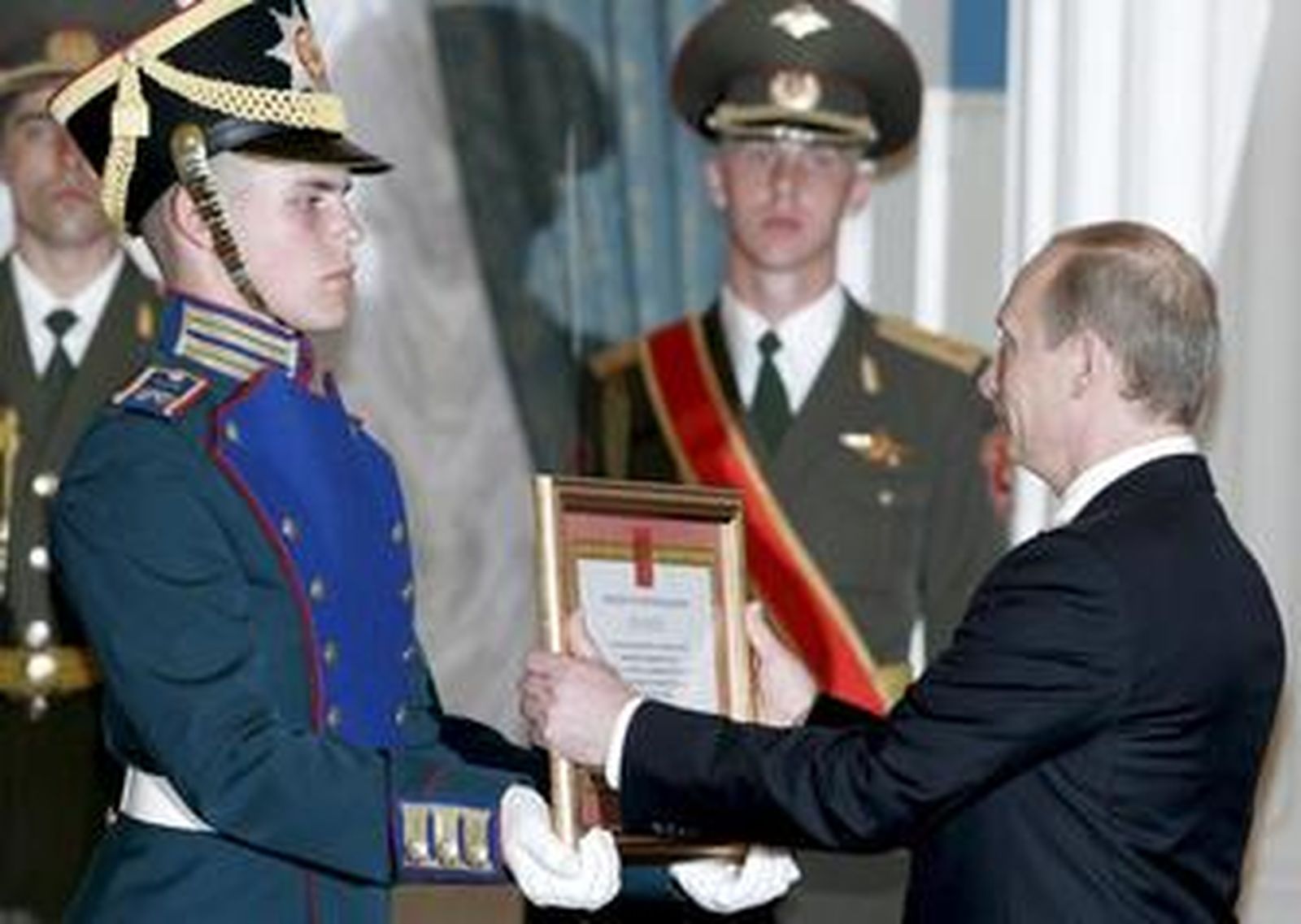 Vladimir Putin recibe el premio del Estado de manos de un guardia del Kremlin.