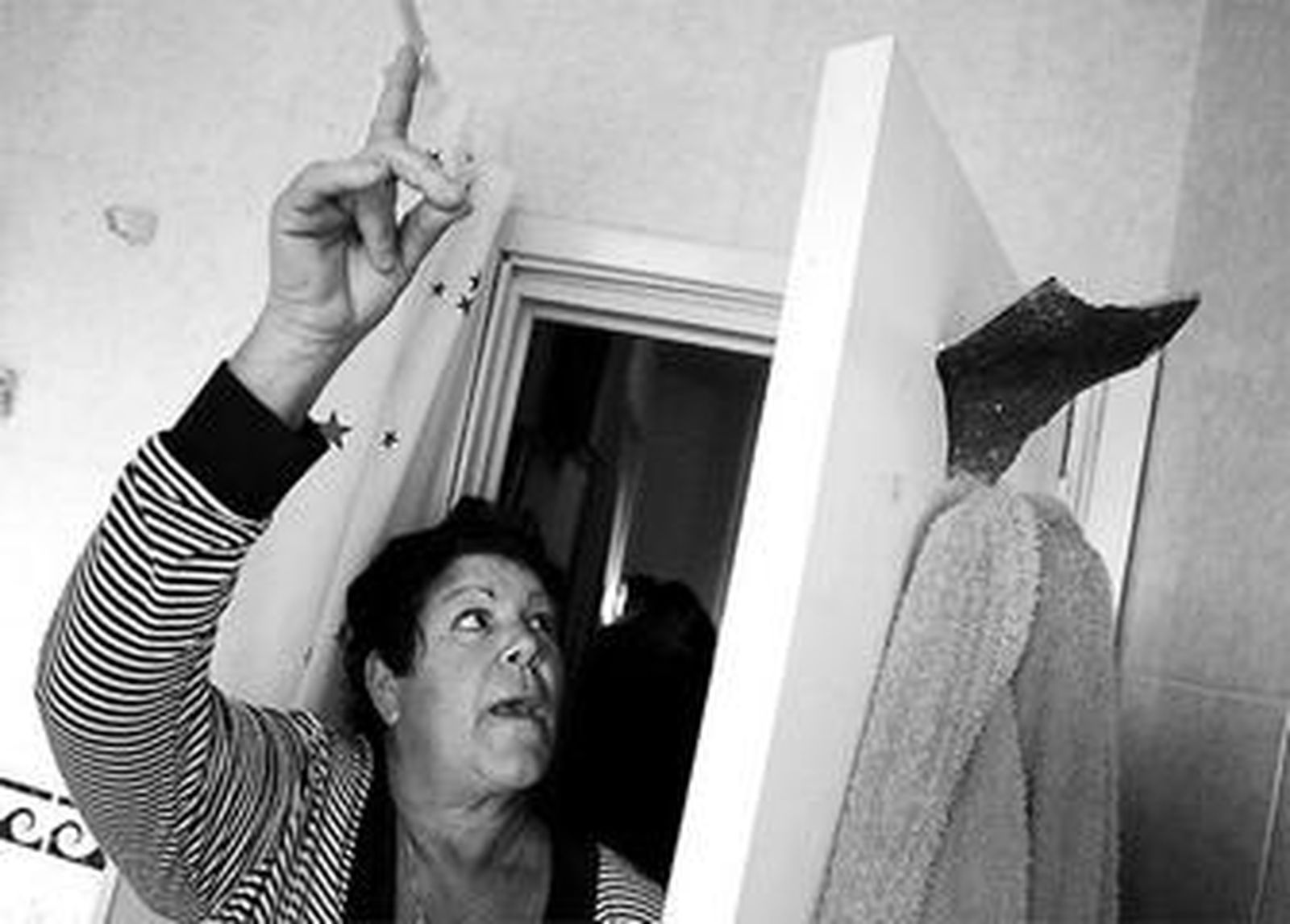 Dolores Soria muestra cómo un trozo de teja se clavó en la puerta de su cuarto de baño.