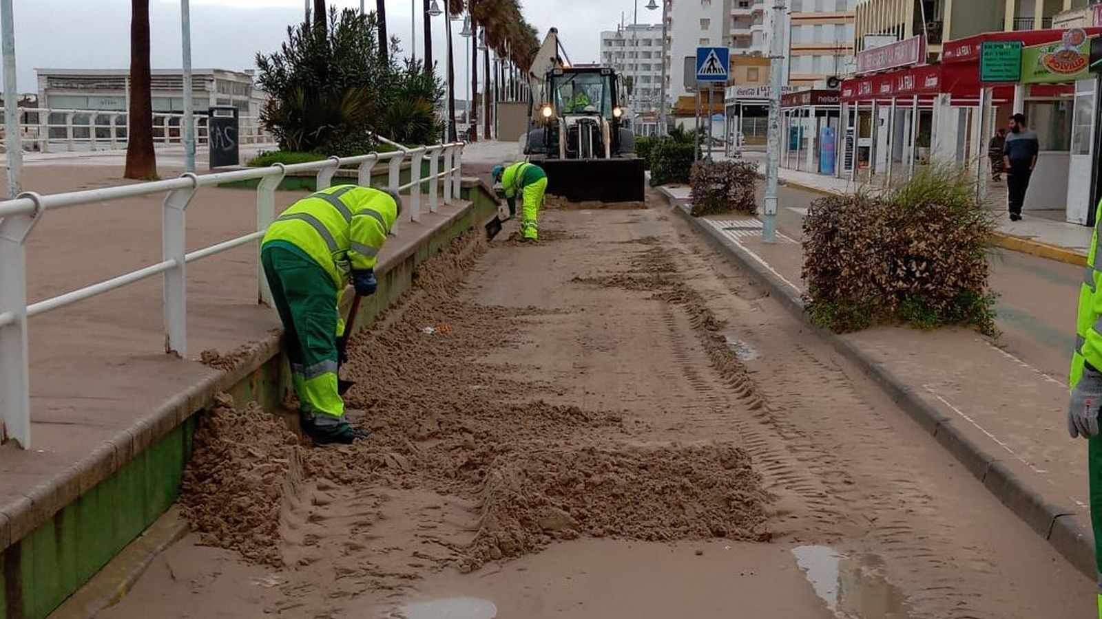 Operarios municipales retirando arena del Paseo Marítimo de Valdelagrana.