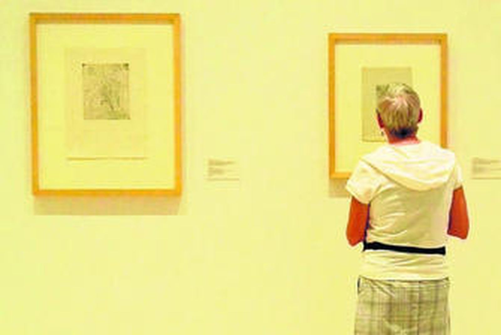 Una visitante observa dos grabados de la muestra.