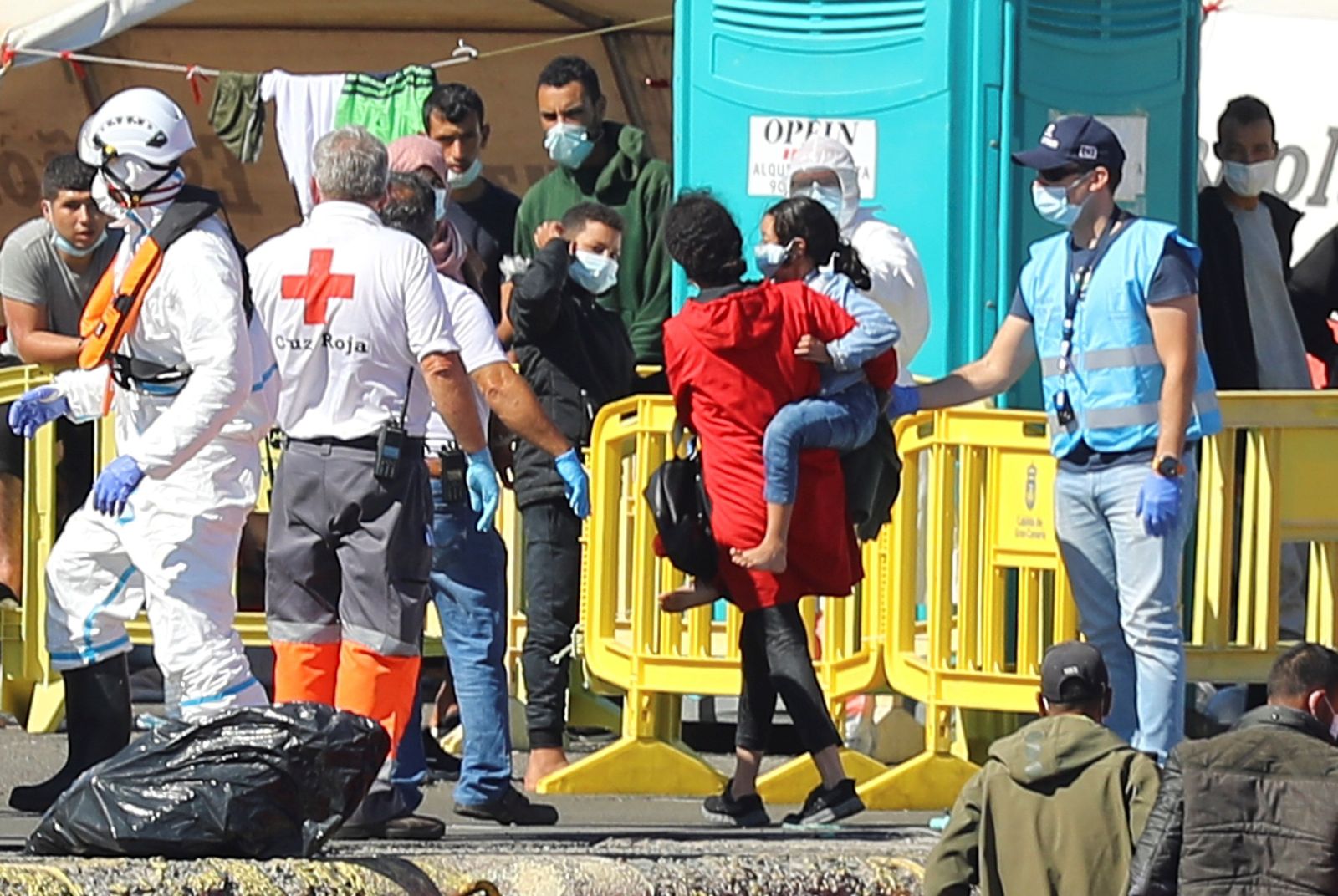 Miembros de la Cruz Roja ayudan a los inmigrantes recluidos en el muelle de Arguenaguín.