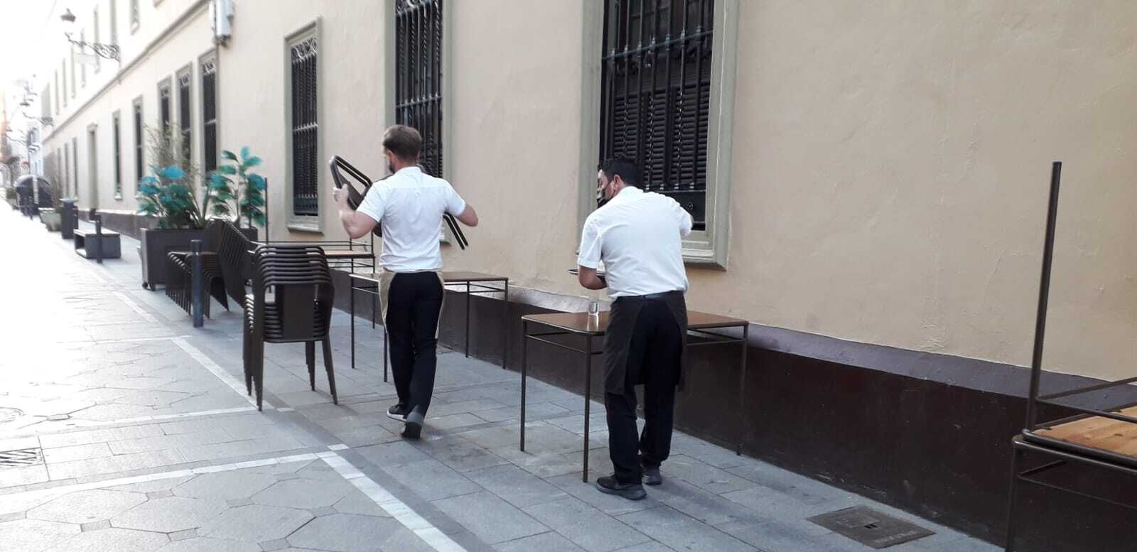 Camareros recogiendo mesas antes de la hora de cierre decretada.