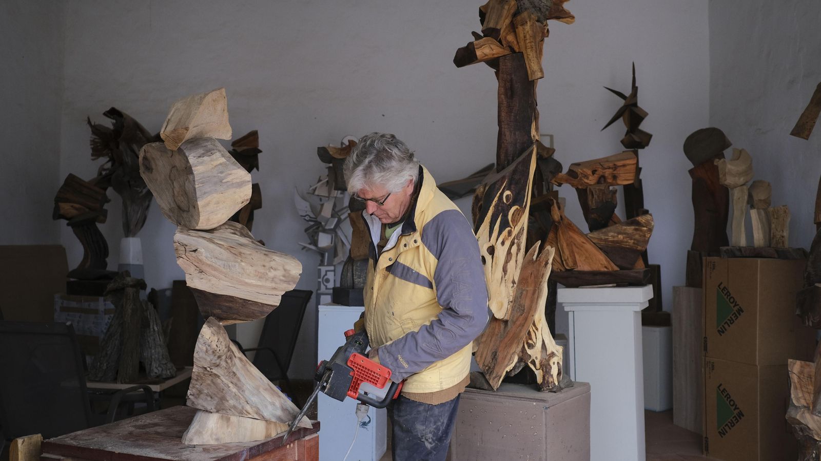 Un artista, en su taller, modela una pieza de madera.