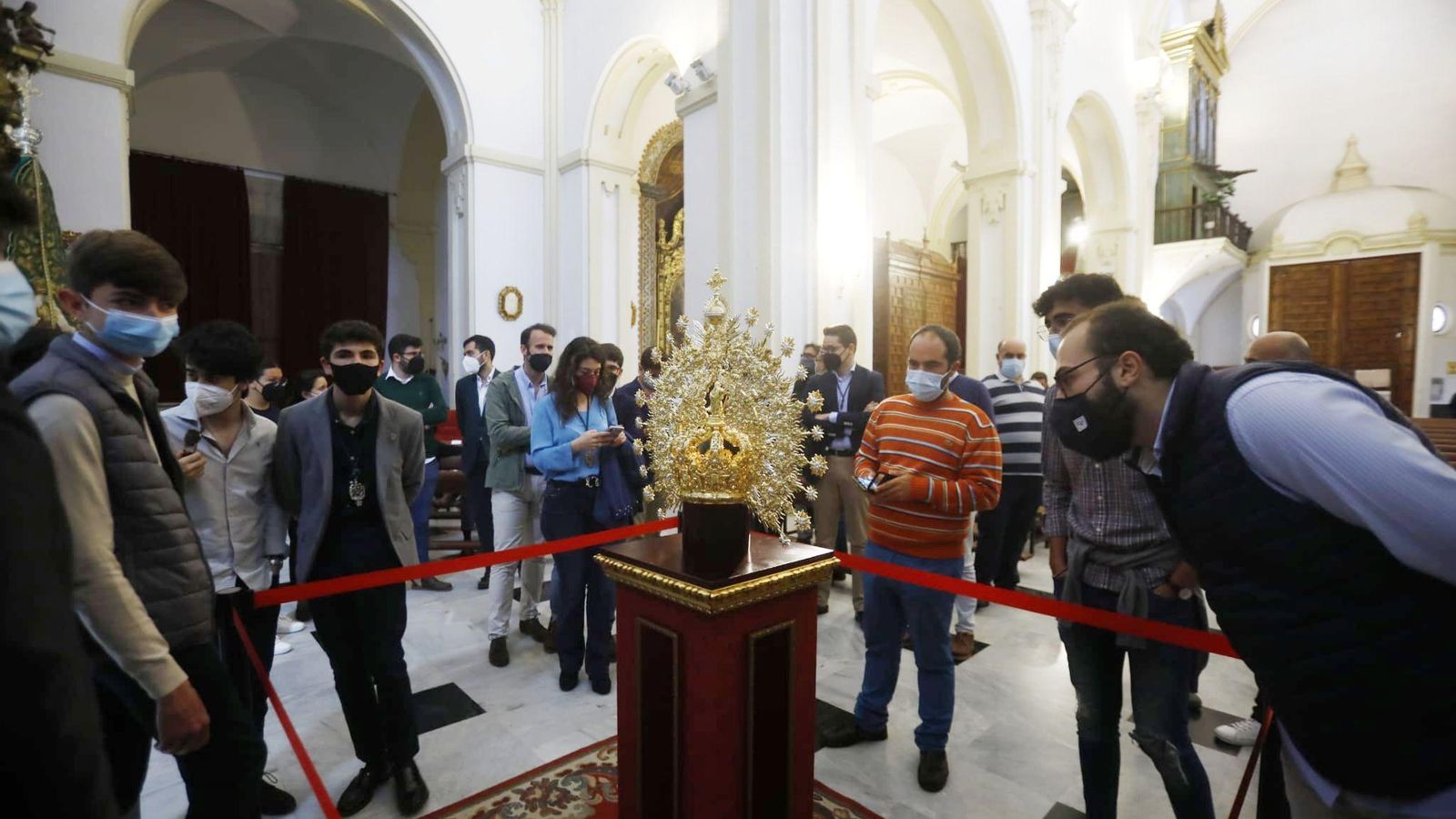 Varias personas observan la nueva corona de la Virgen de la Esperanza.