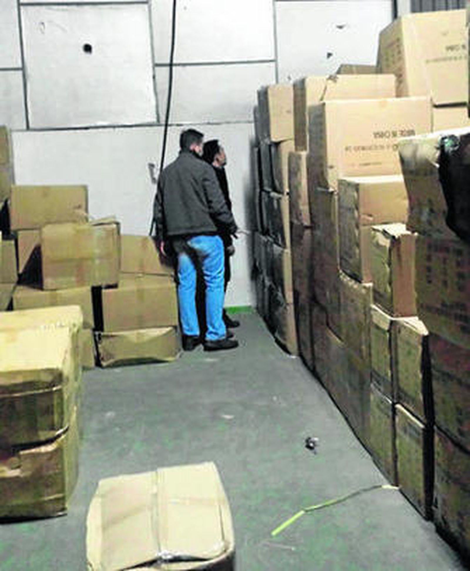 Dos agentes del Grupo Fiscal inspeccionan el almacén.