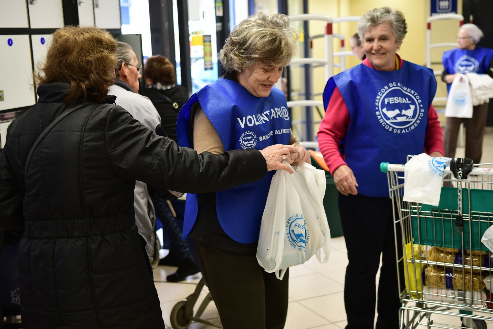 Una señora entrega una bolsa con alimentos a una de las voluntarias.