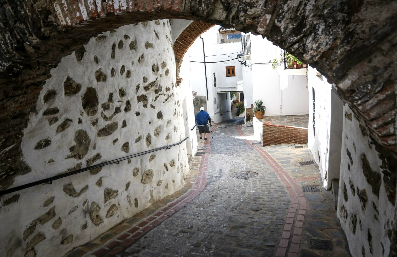 Una vecina camina por una de las empinadas calles de Jubrique.
