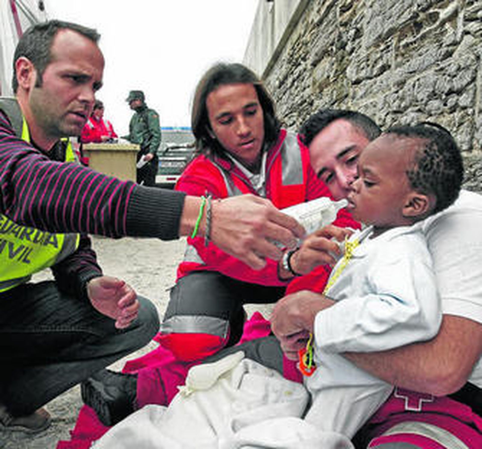 Un agente de la Guardia Civil da el biberón a un bebé atendido por Cruz Roja, ayer en el puerto de Tarifa.