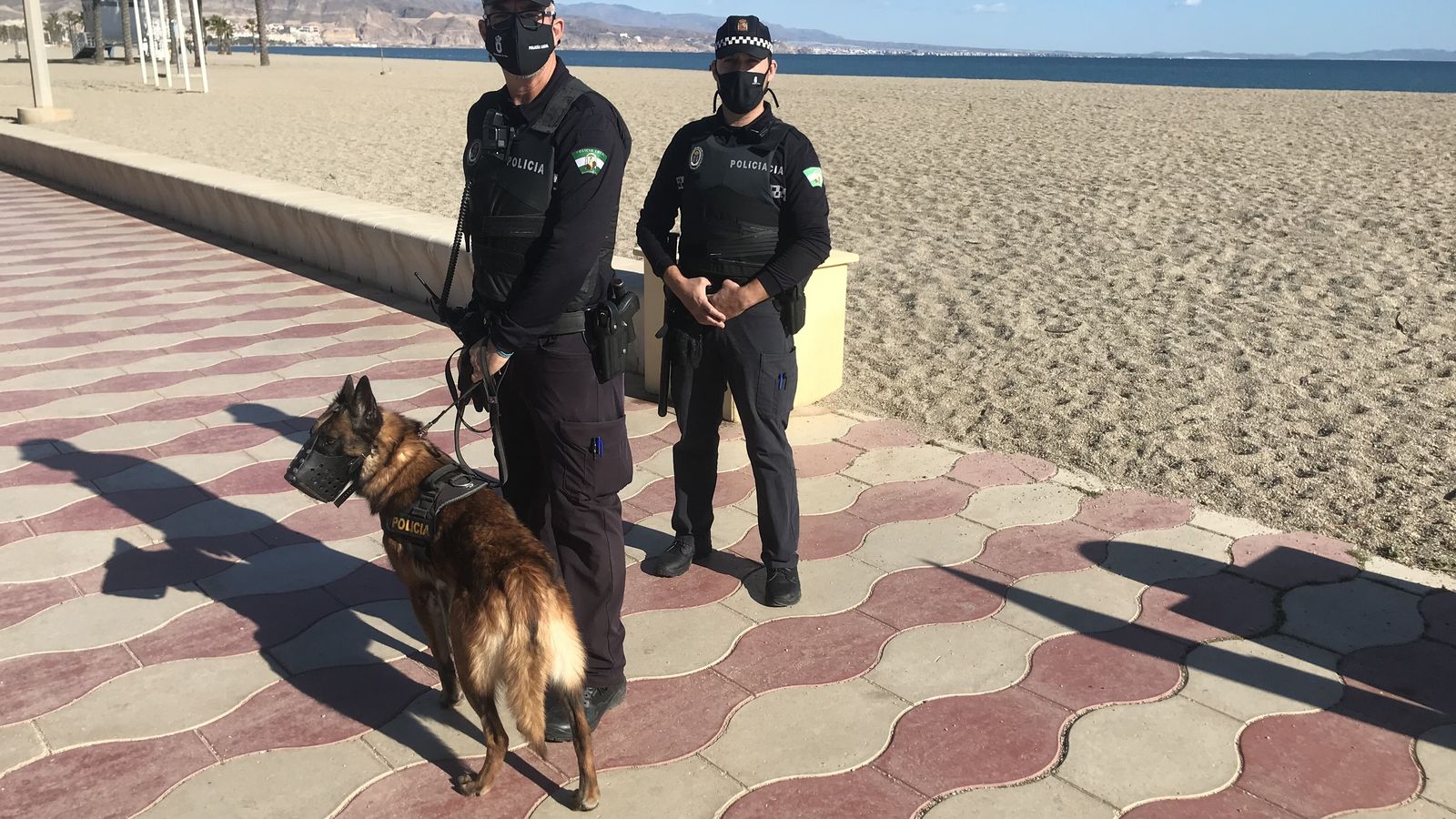 Dos agentes de la Policía Local patrullan por la Playa de La Romanilla de Roquetas de Mar.