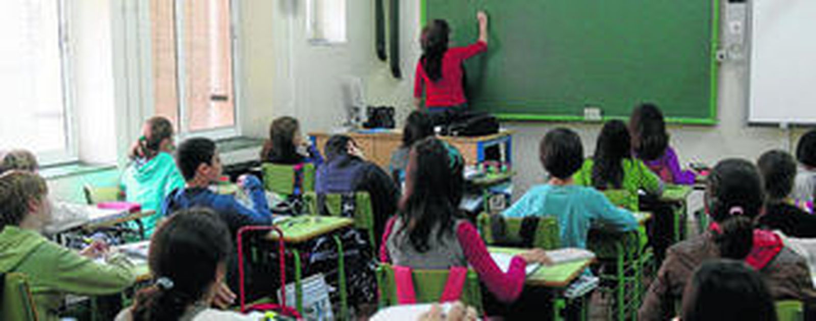 Una profesora escribe en la pizarra durante el desarrollo de una clase en el Instituto San Isidoro.