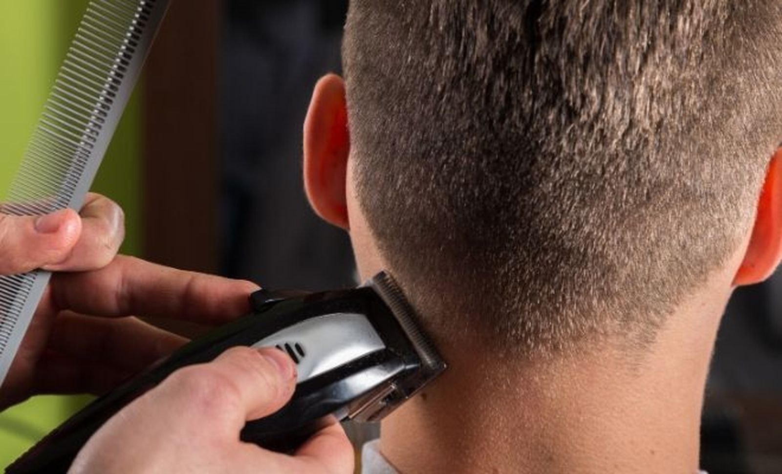 Un peluquero rapa la nuca a un cliente.