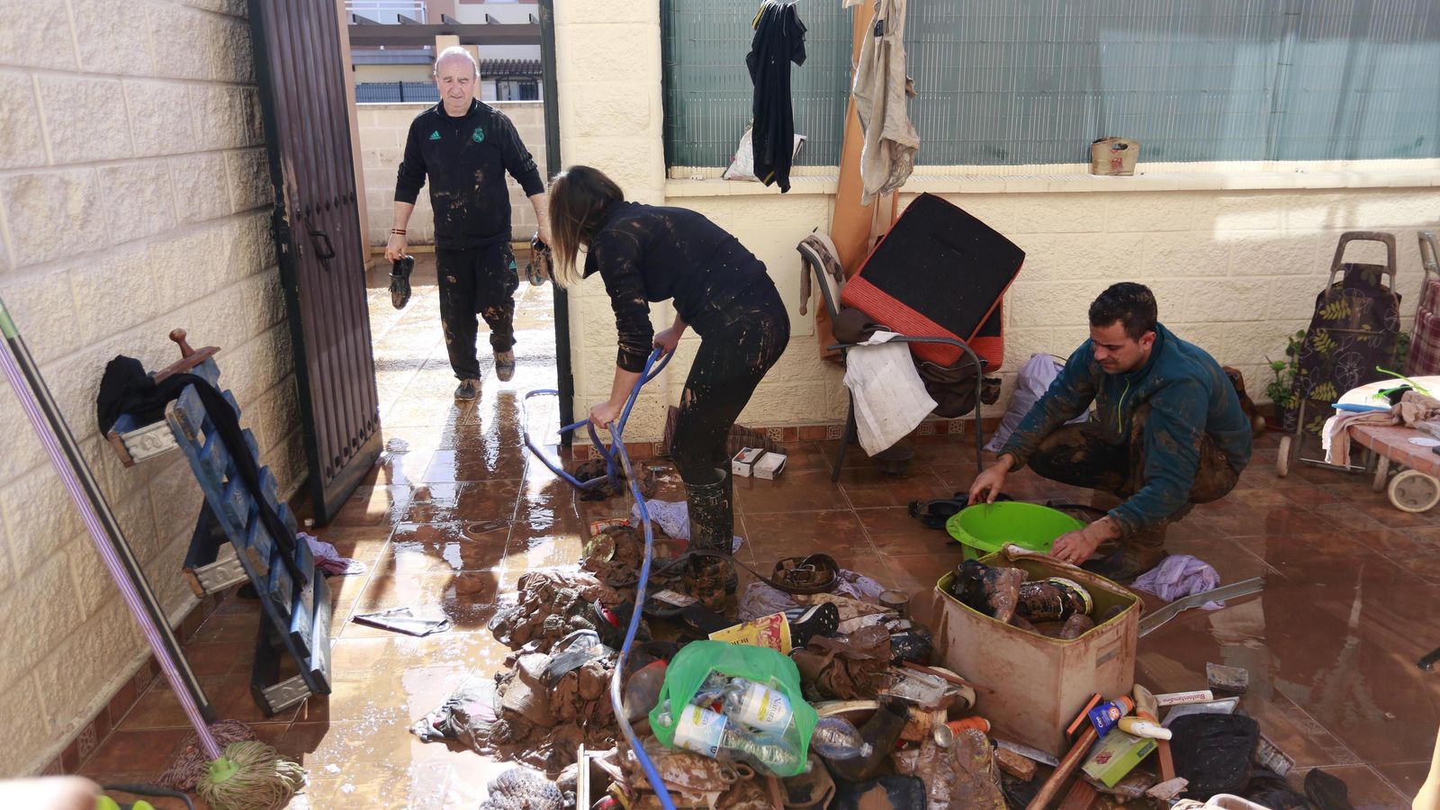 Varios vecinos limpian el barro dejado por la borrasca.