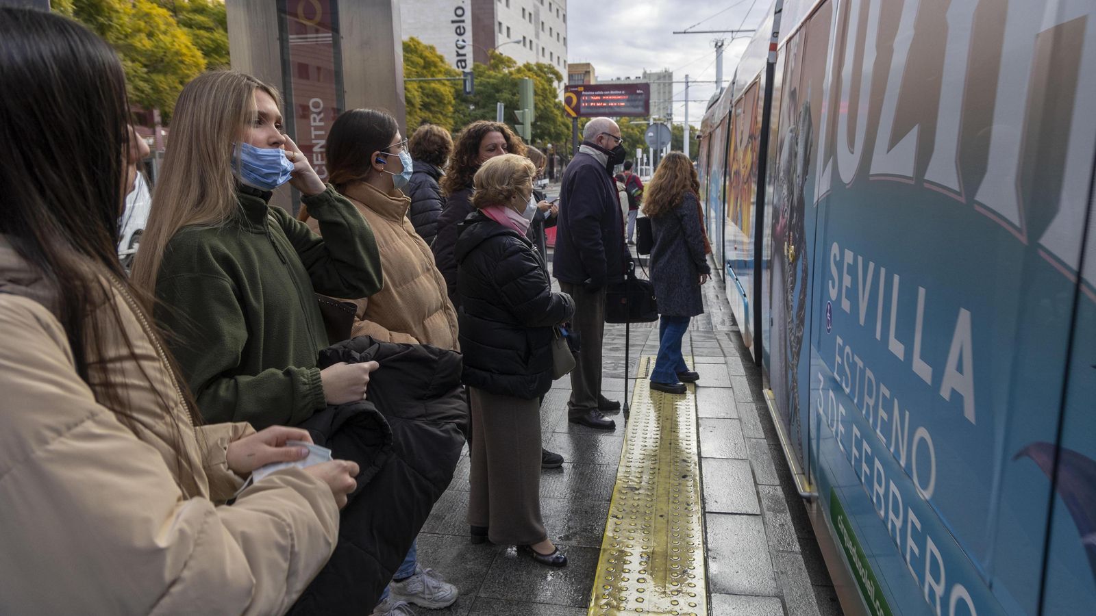 Varias personas esperan para montarse en el tranvía en la parada de San Bernardo, con mascarilla.