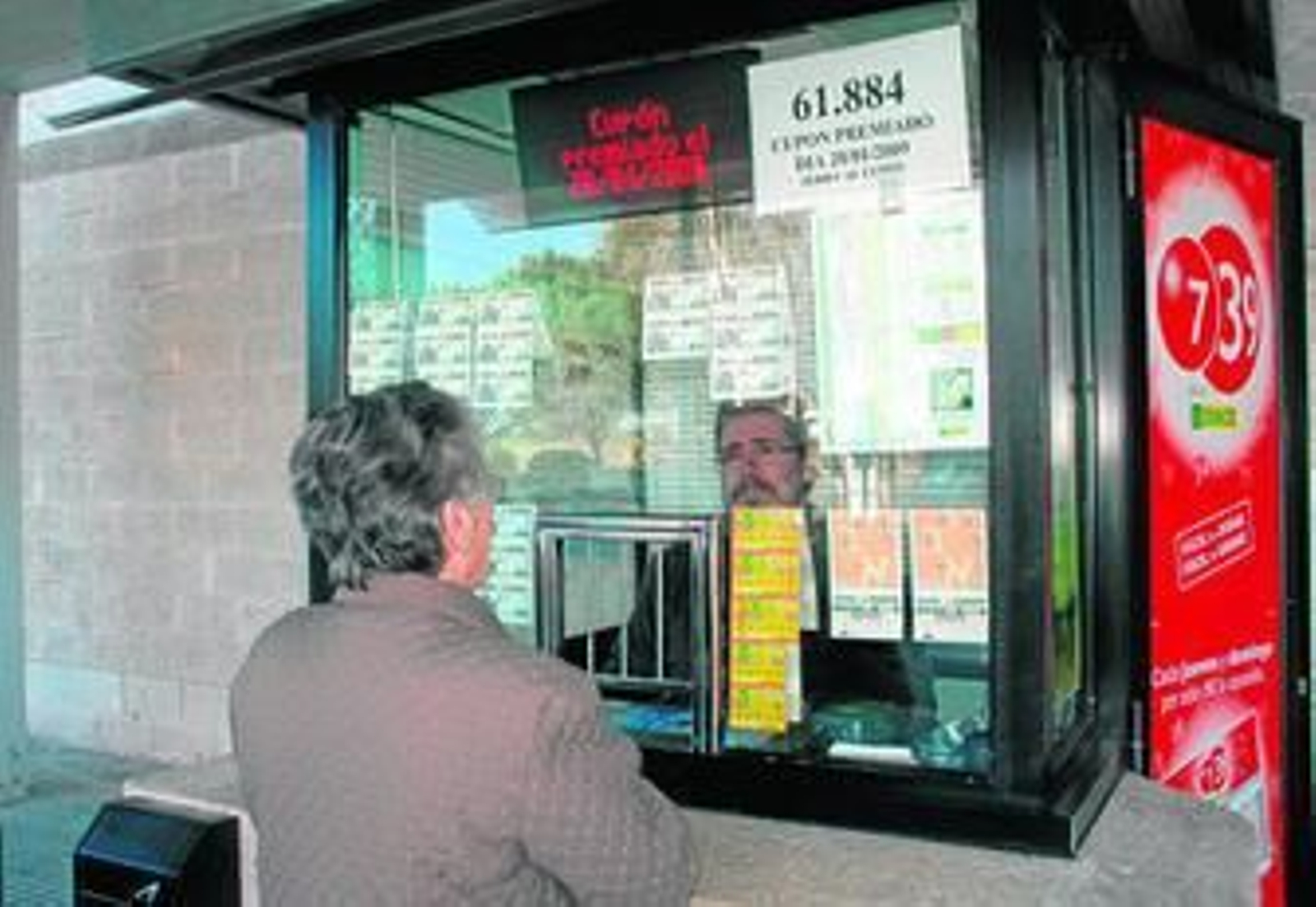 Una mujer compra un cupón en un quiosco de la ONCE.