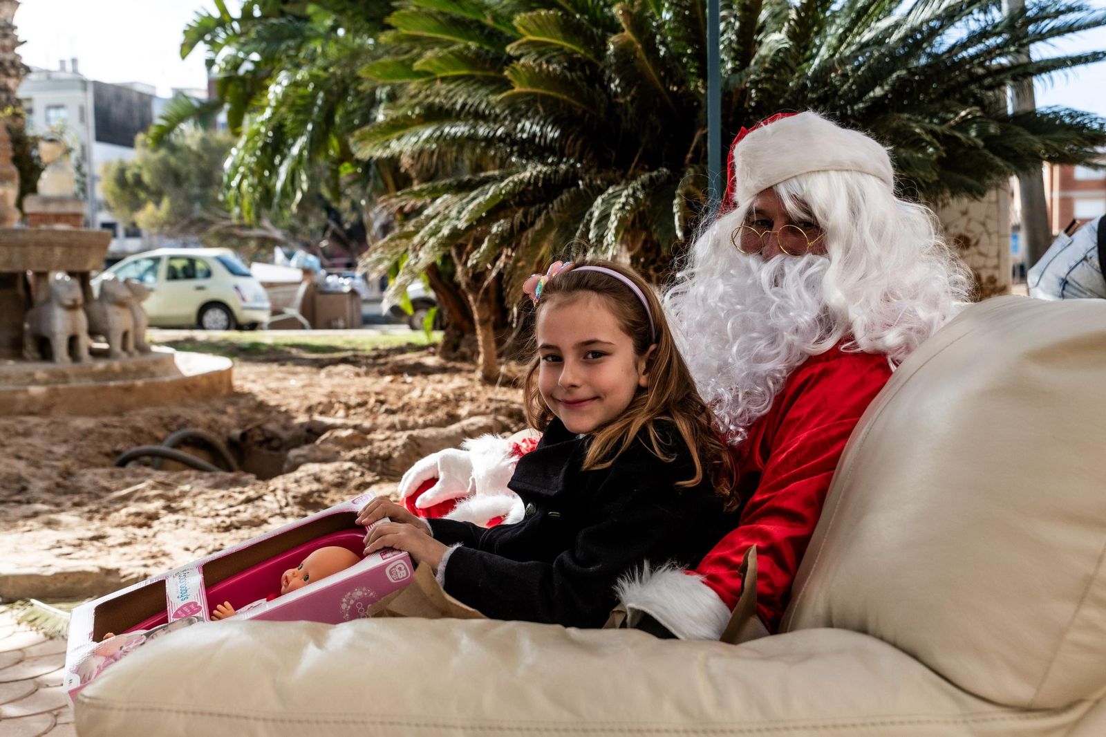 Papa Noel ofrece regalos en un sofá entre destrozos.
