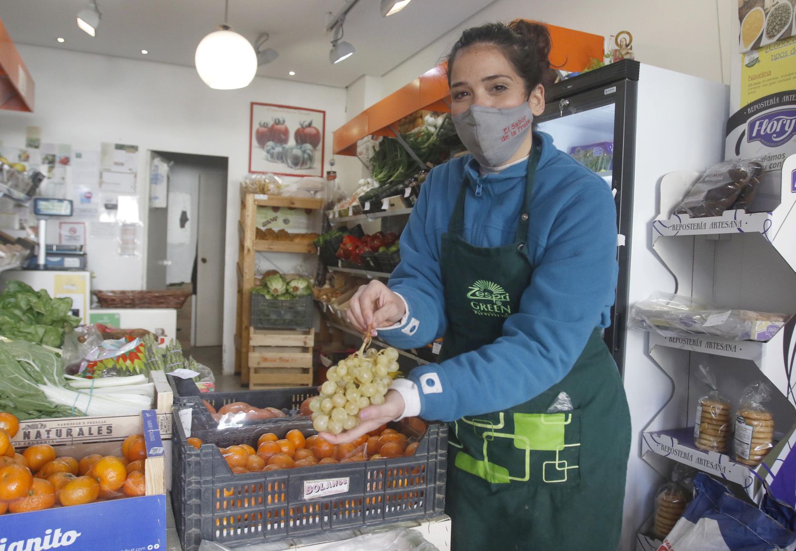 La encargada de El sabor de la fruta, Rocío Moreno, sostiene un racimo de uvas.