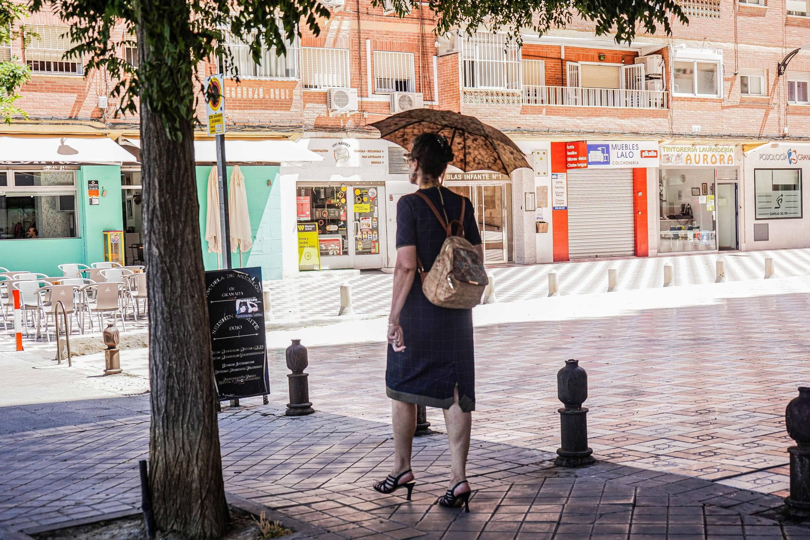 Una mujer se protege del sol mientras camina por Granada.
