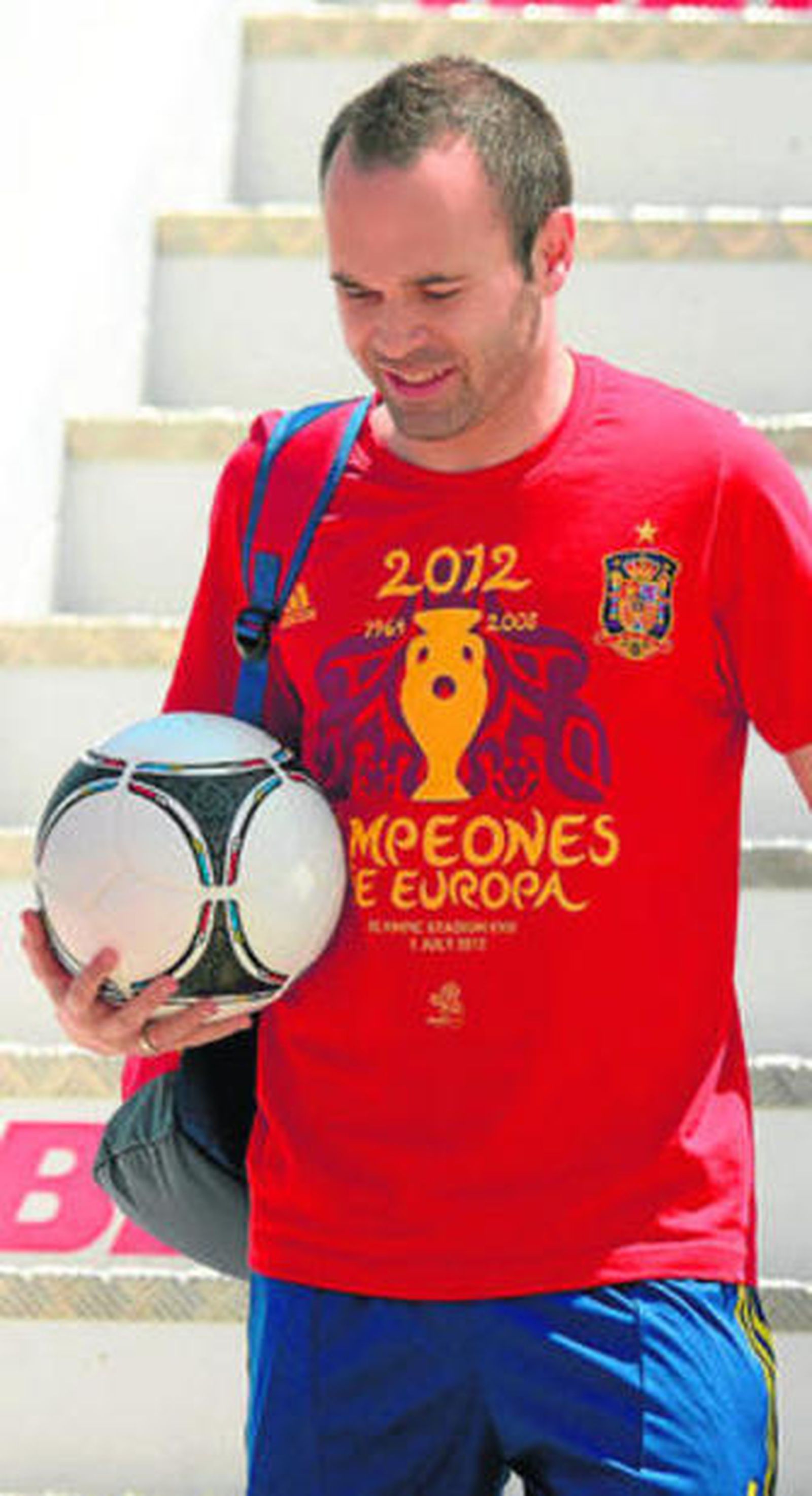 Iniesta, con el balón en la mano, baja del avión en Barajas.
