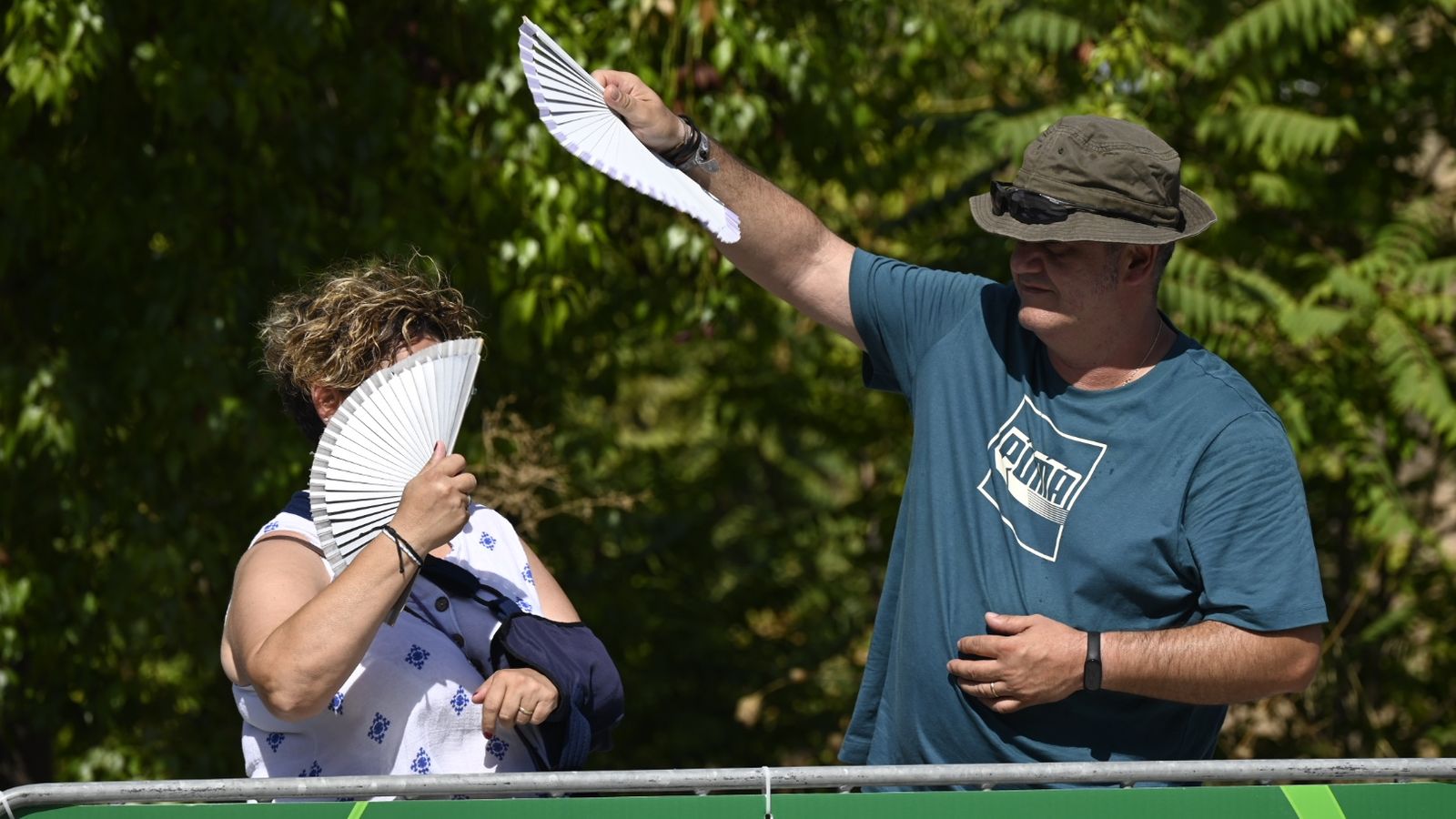 Dos aficionados se protegen del sol en la línea de meta.