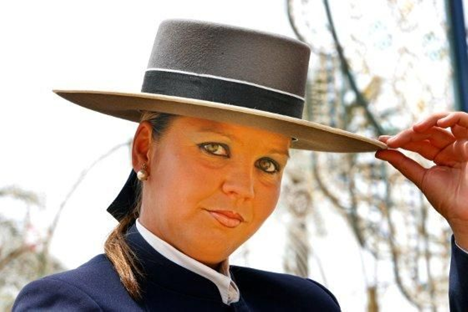 Una guapa joven posa en el recinto feria sosteniendo su sombrero de ala ancha

Foto: pascual