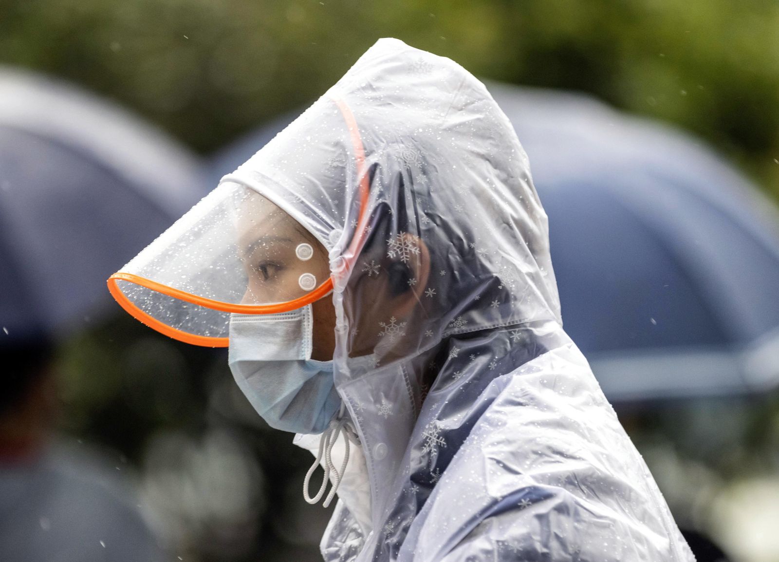 Una mujer, protegida con pantalla y mascarilla, camina por las calles de la ciudad china de Guangzho.