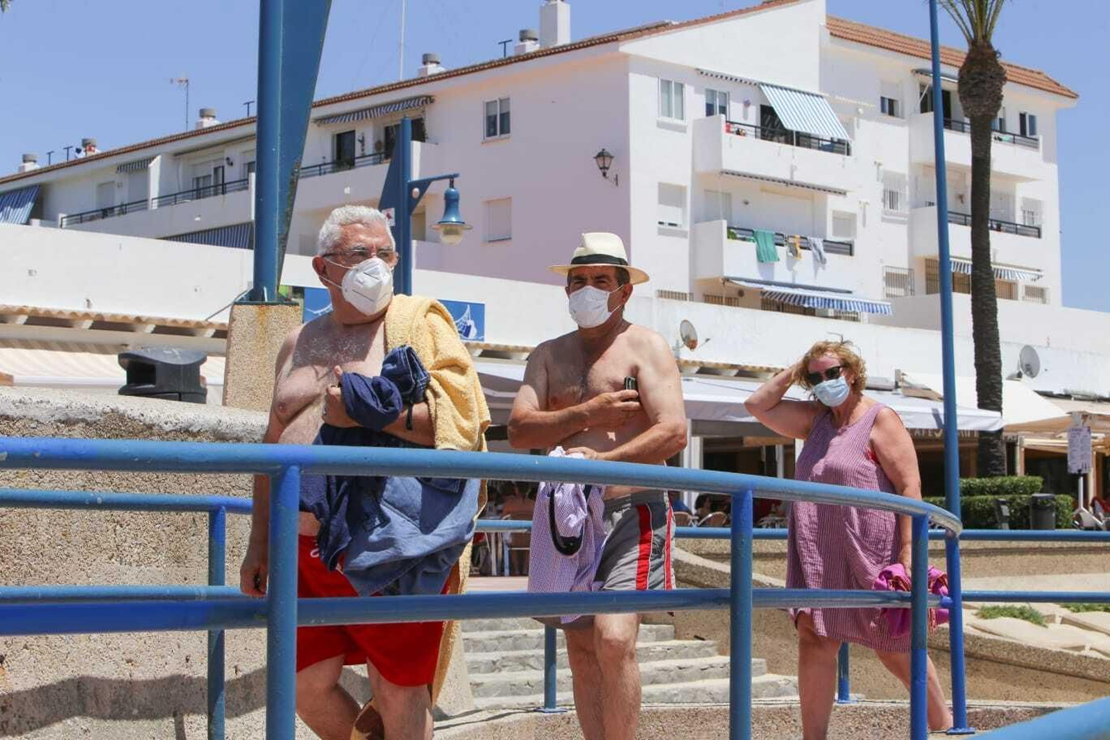 Varias personas salen de la playa, en la mañana de hoy miércoles, con las mascarillas colocadas.