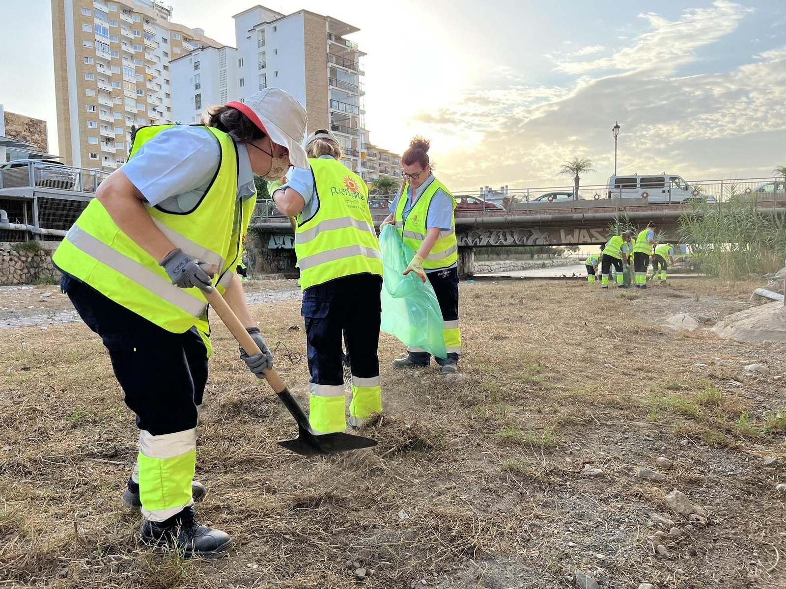 Unas operarias retiran maleza del cauce del arroyo Pajares, en Fuengirola.