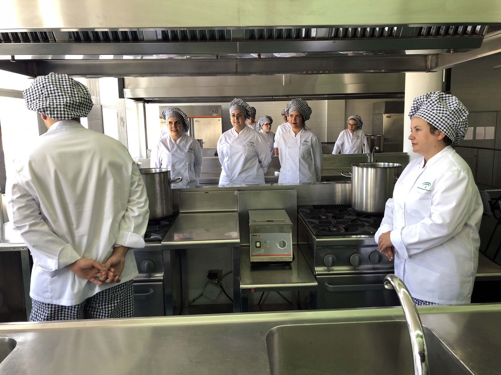 Alumnos de la Escuela de Hostelería de Islantilla aguardan el paso de la comitiva de autoridades en el acto de inauguración oficial del curso celebrado ayer.