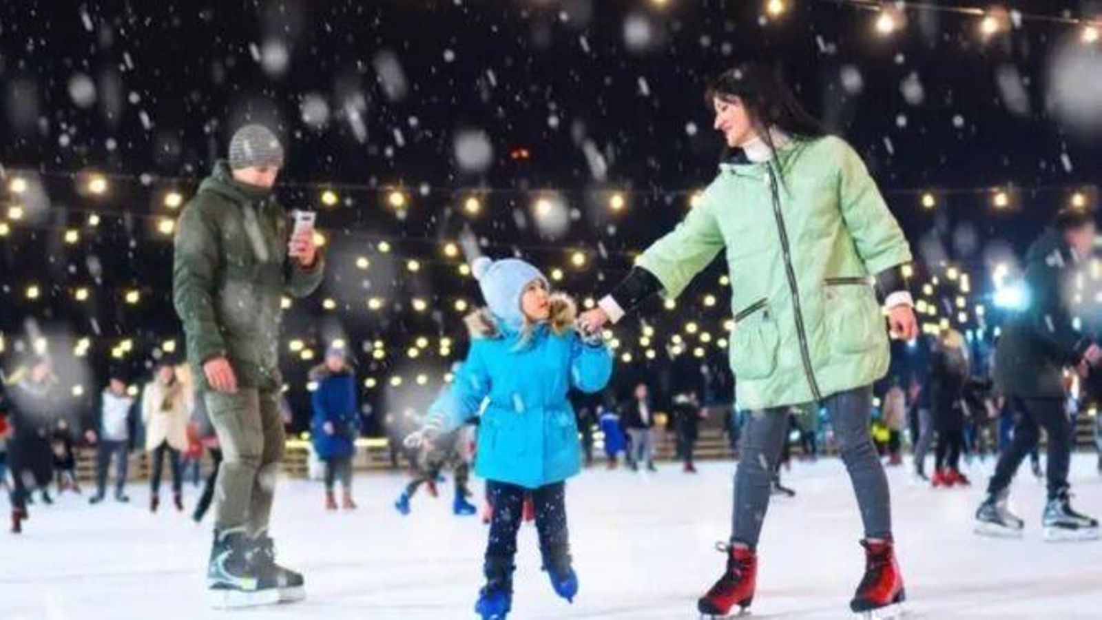 Una mujer y su hija patinan en una pista de hielo