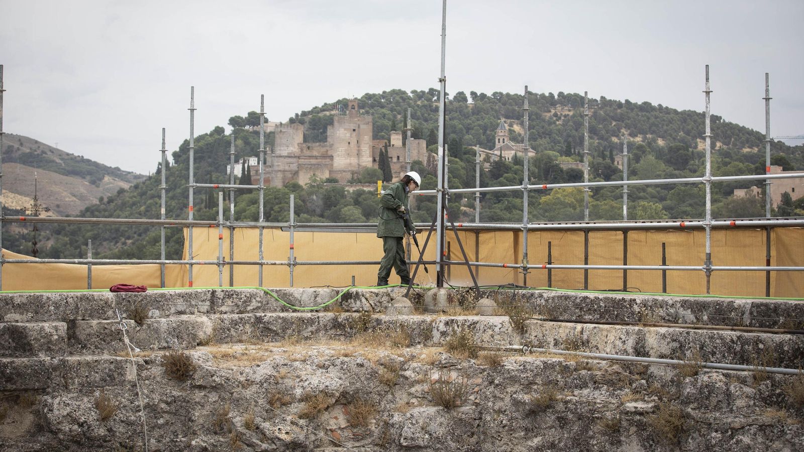 Labores de limpieza de la piedra con hidrolimpiadora, con la vista de la Alhambra de fondo.