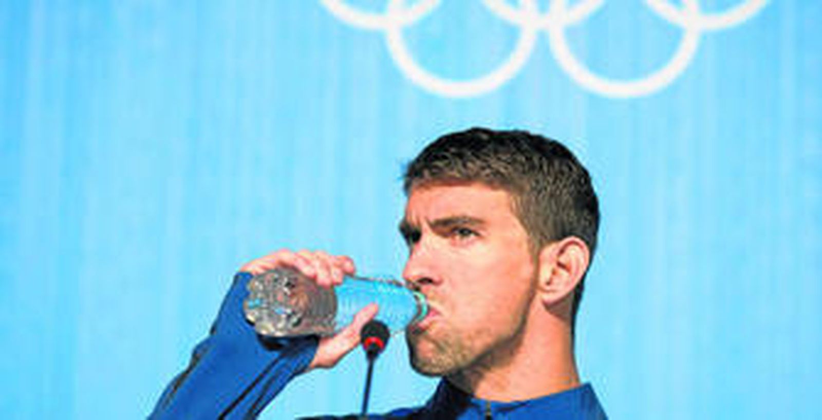 Michael Phelps bebe agua durante su comparecencia ante los medios en el Parque Olímpico de Río de Janeiro.