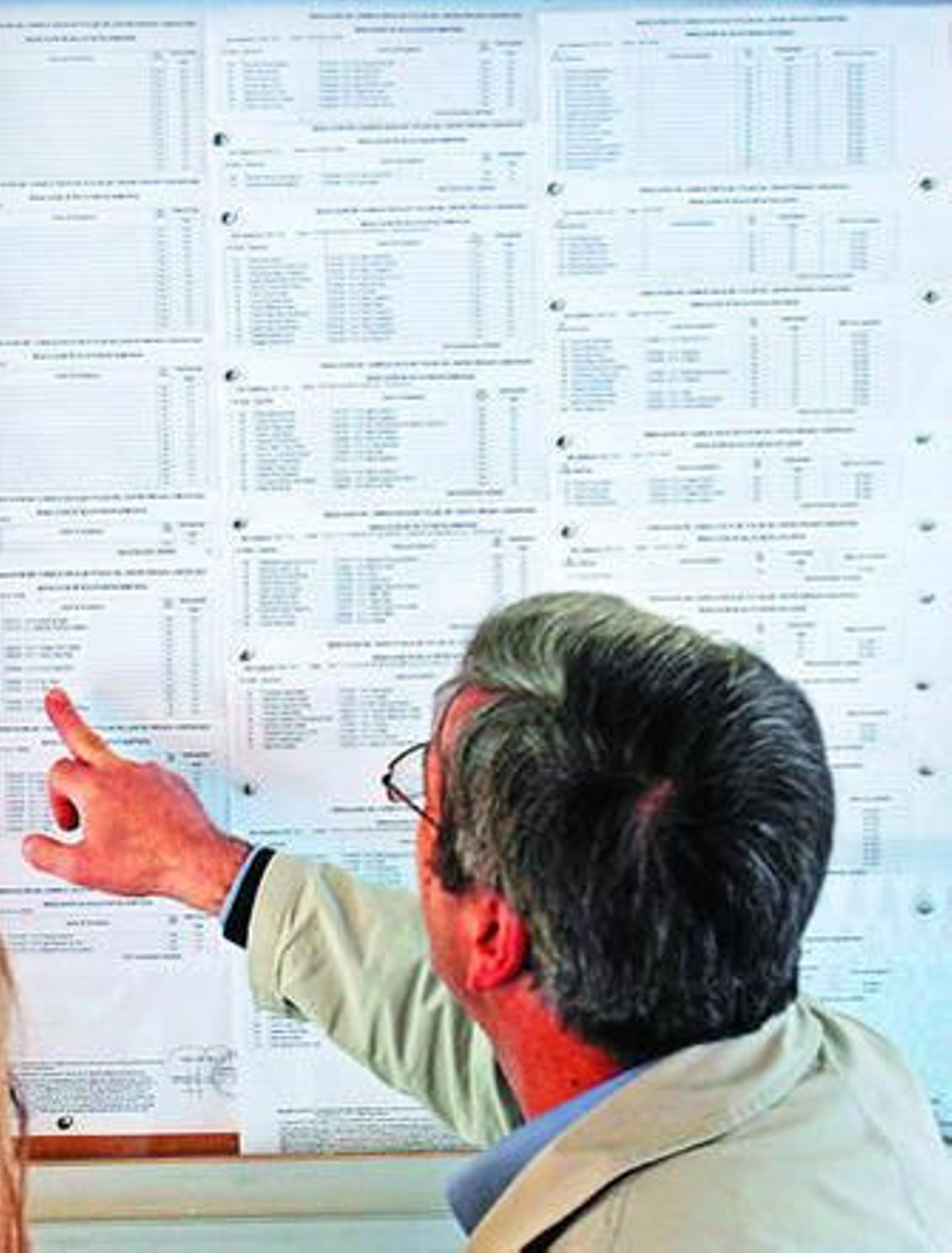 Un adulto consulta un listado de admisión de alumnos en el colegio Salesianos.