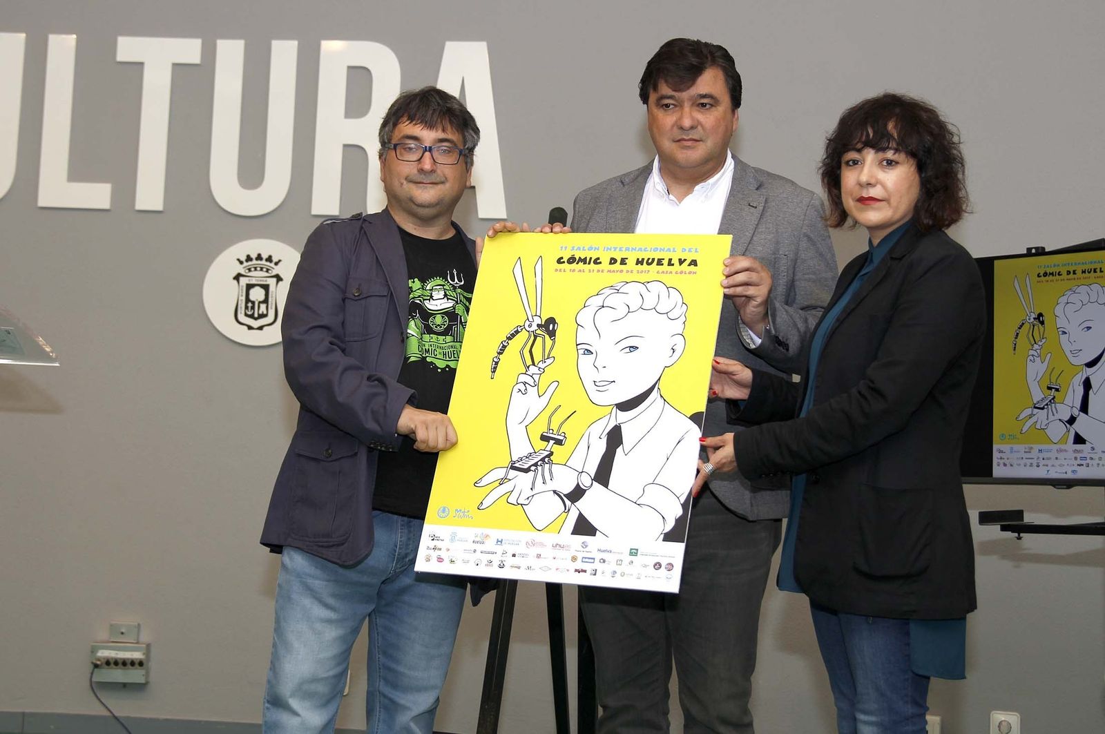 El director del Salón Internacional del Cómic, Gerardo Macías; el alcalde de Huelva, Gabriel Cruz; y la concejal de Cultura, Elena Tobar, con el cartel.