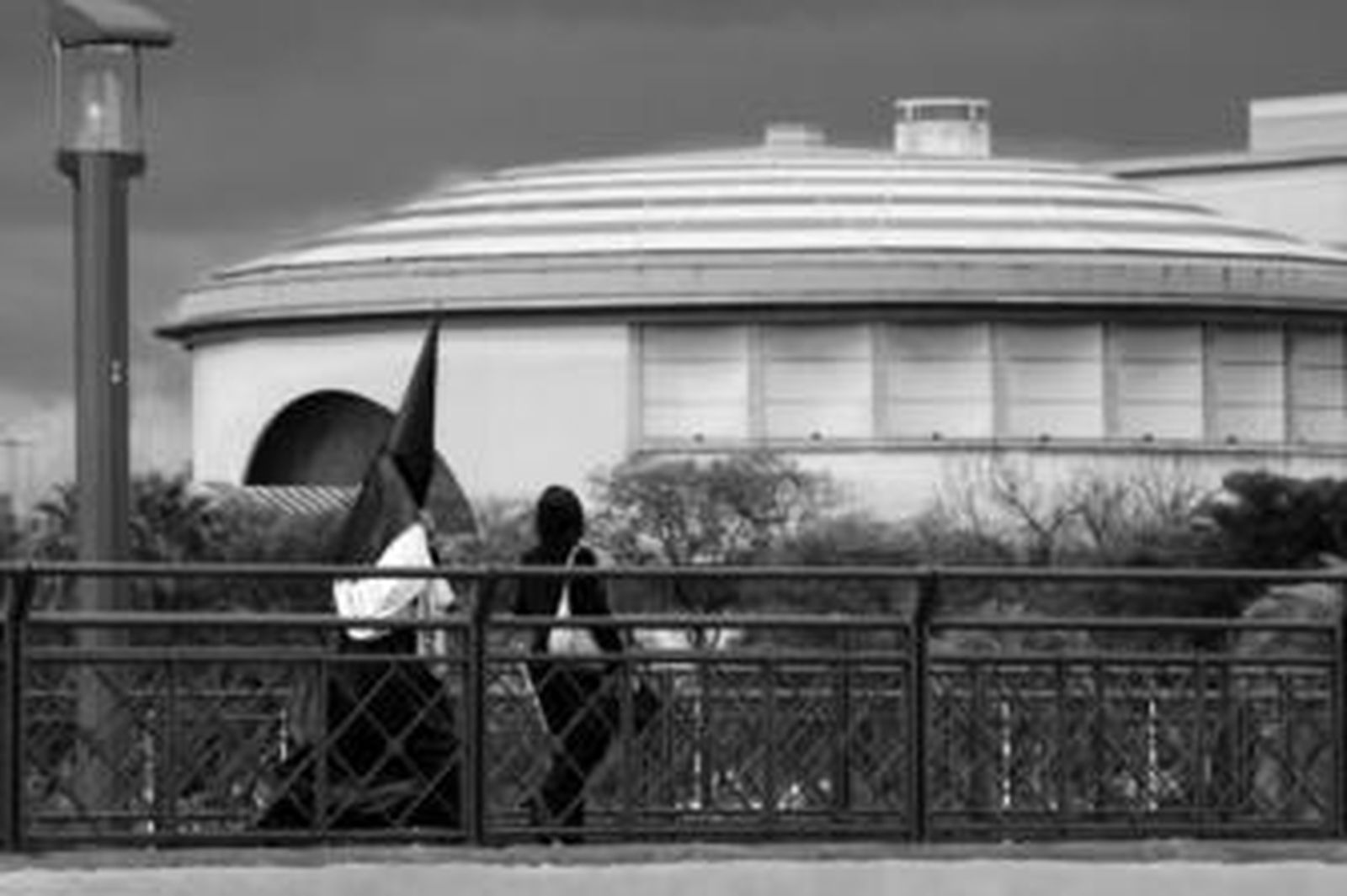 Un nazareno regresa a casa por el puente de San Telmo después de que la hermandad decidiera no procesionar.