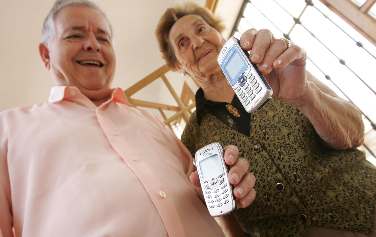 Imagen de archivo de una pareja de personas mayores con móviles en sus manos
