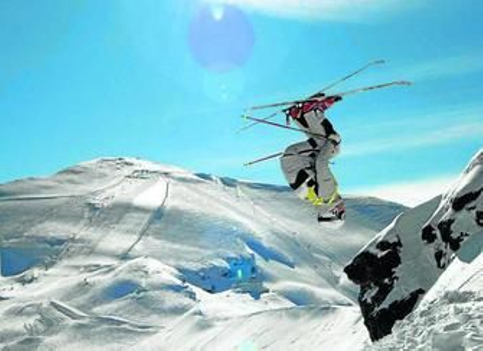 Arriba, un esquiador acomete un acrobático salto de un esquiador ante la majestuosa estampa de las rampas de la Sierra de Nevada de fondo. Abajo, un monitor imparte lecciones a dos iniciados en el mundo del esquí en las pistas de la estación granadina.