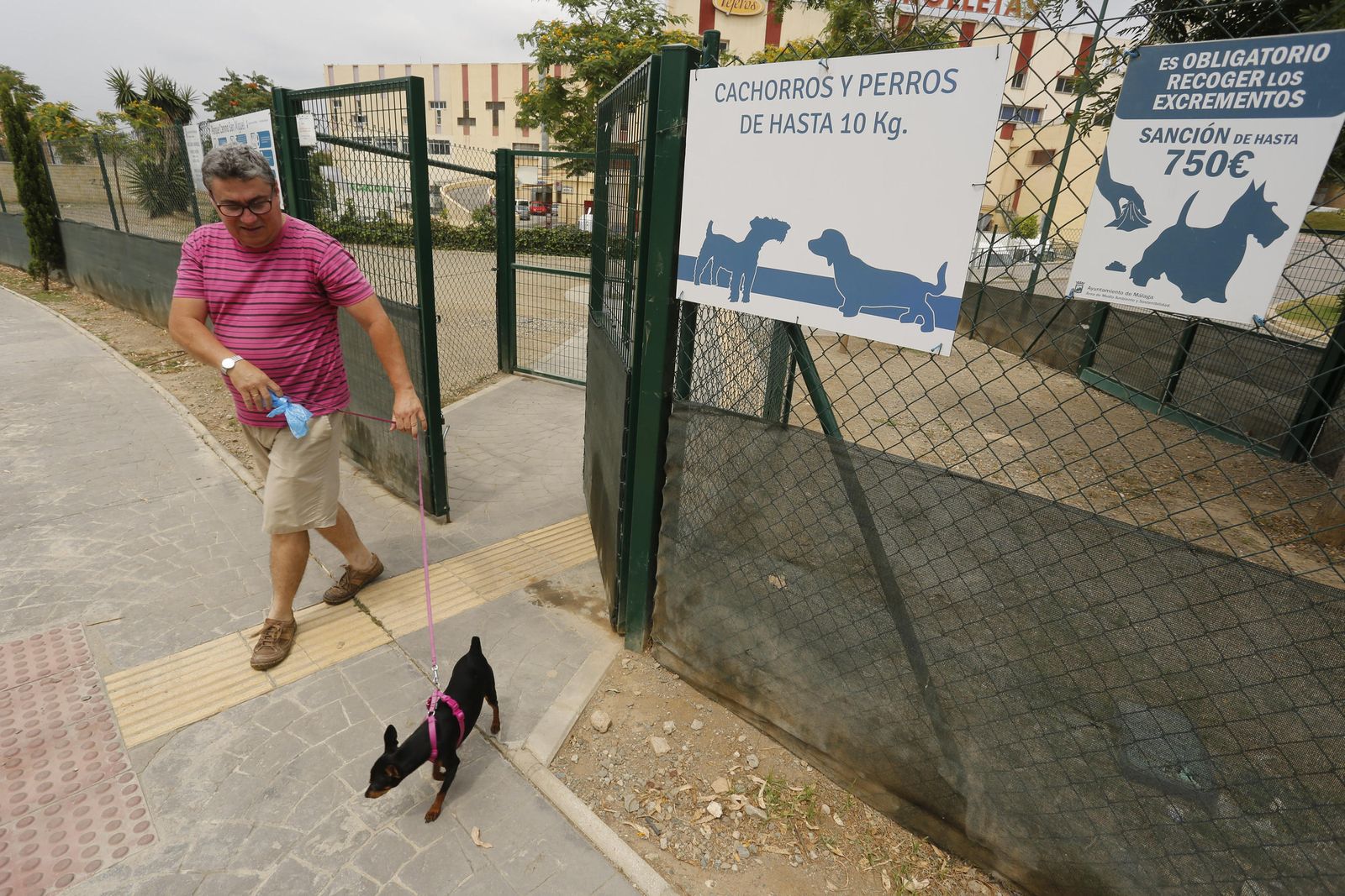 Un hombre pasea con su mascota por un parque canino de la capital.