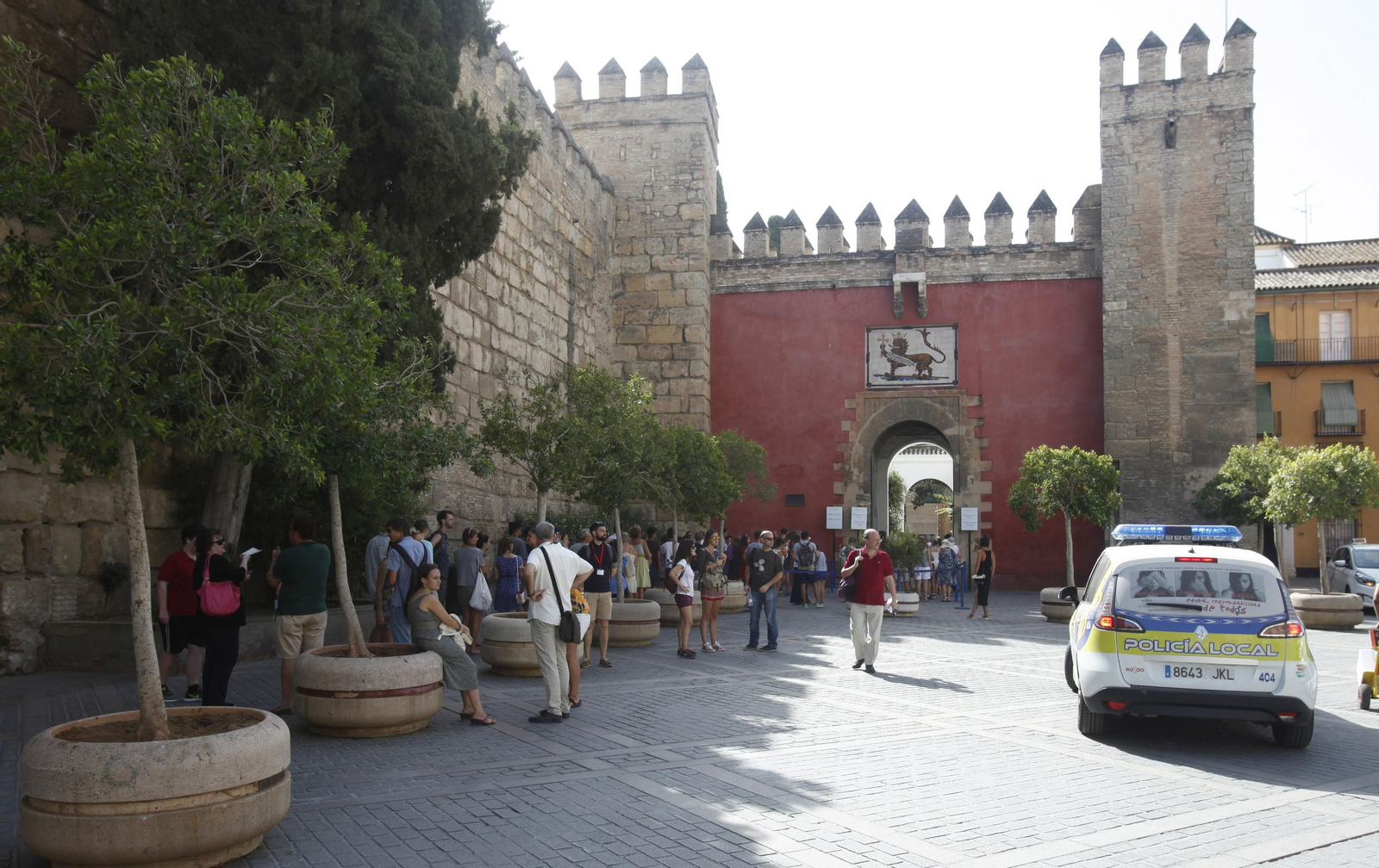 Los macetones preservan a los visitantes que aguardan para entrar en el Alcázar. Al lado, un coche policial vigila el entorno.