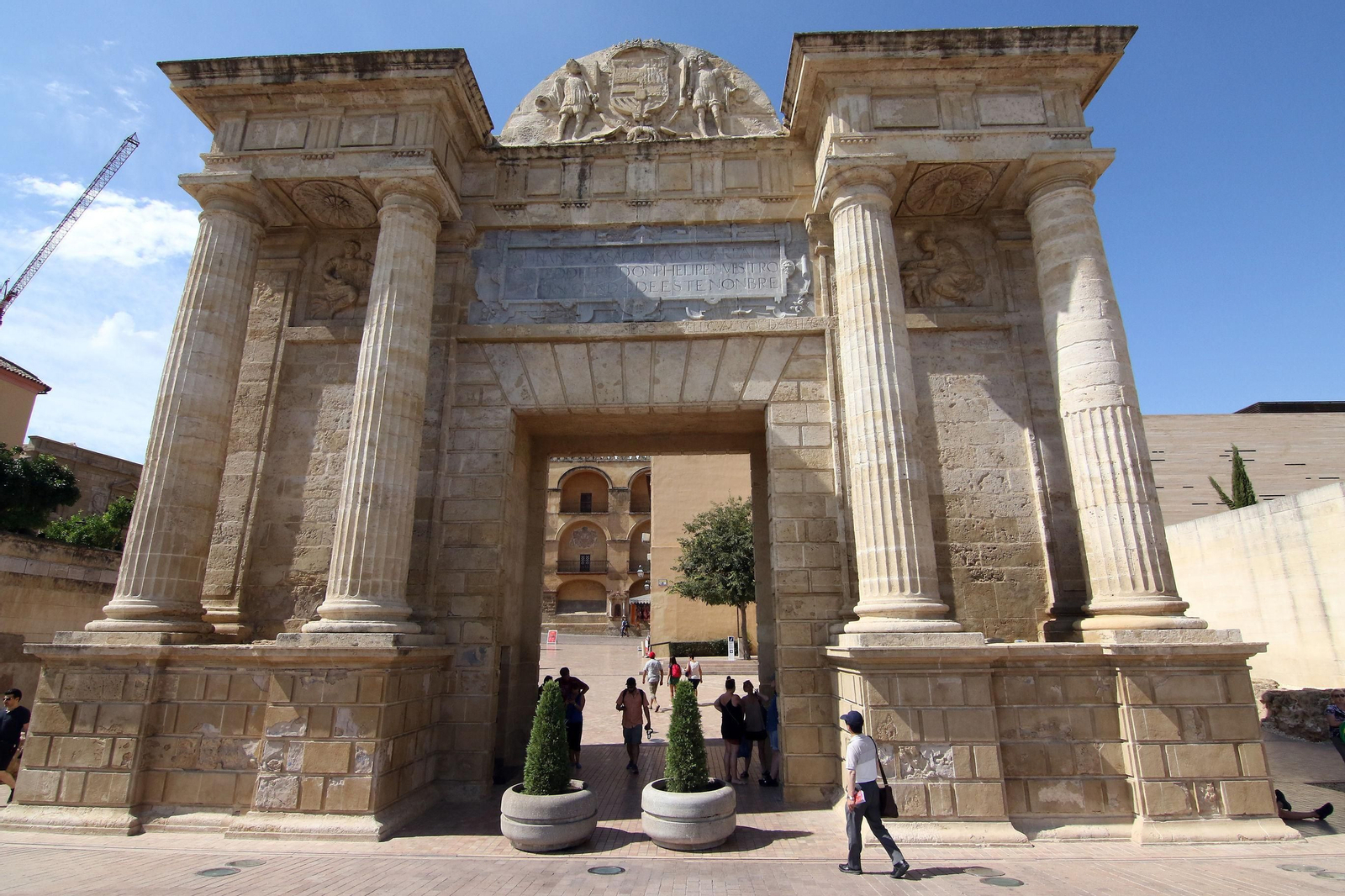 Unos turistas caminan junto a la Puerta del Puente