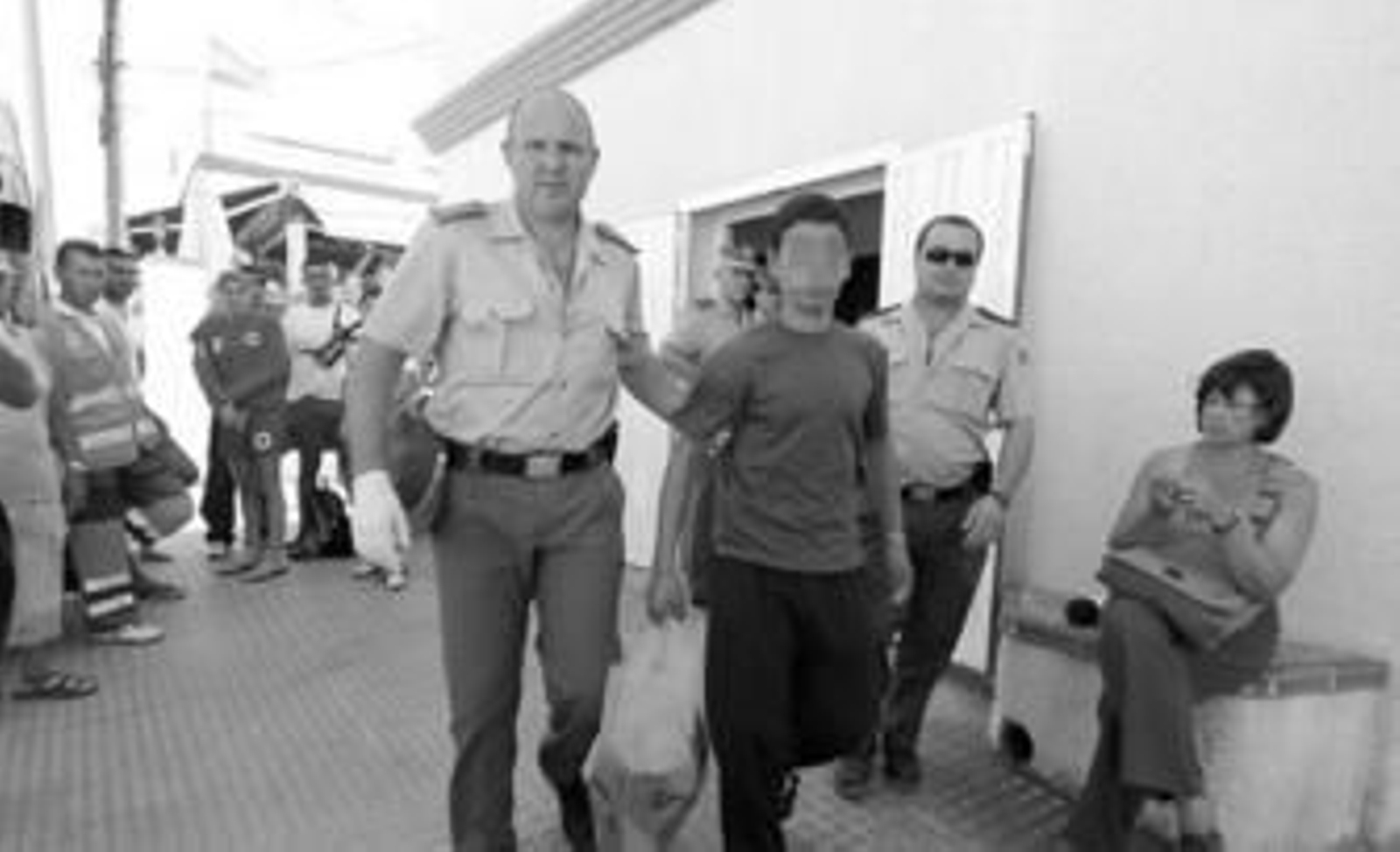 Uno de los inmigrantes interceptados abandona el puesto de la Cruz Roja de La Barrosa, en compañía de agentes de la Guardia Civil.